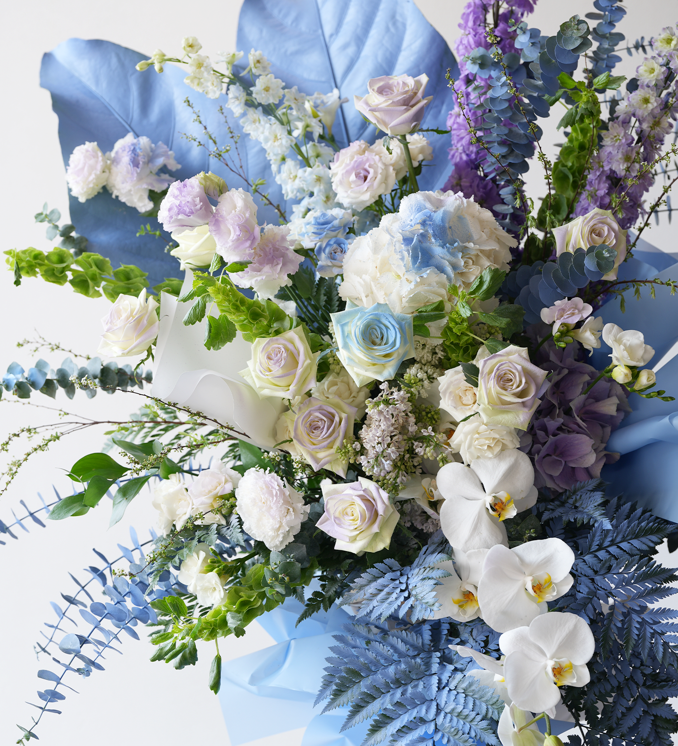 Close-up of Delaney flower stand featuring blue, lilac and white florals with foliage