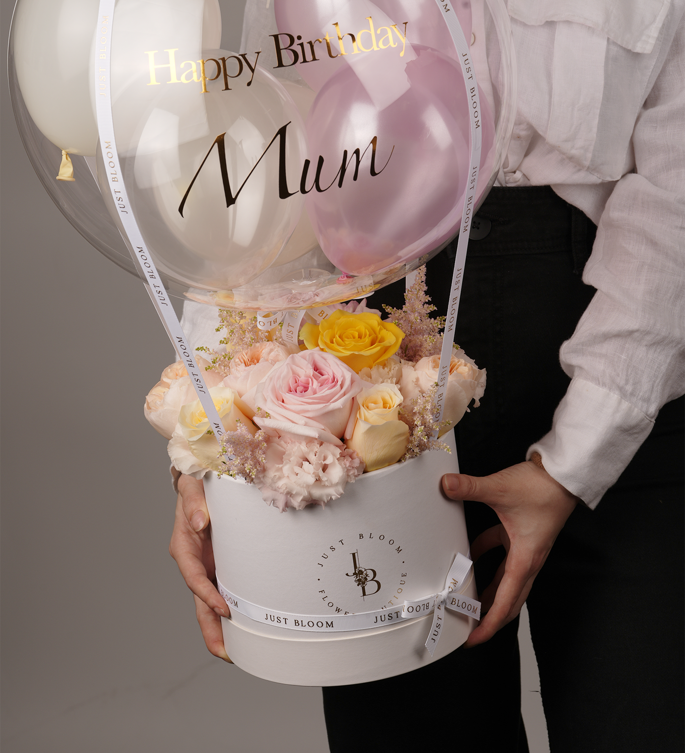Close-up of Bristol flower box showcasing roses, Dutch carnations, and pale pink astilbes with transparent balloon