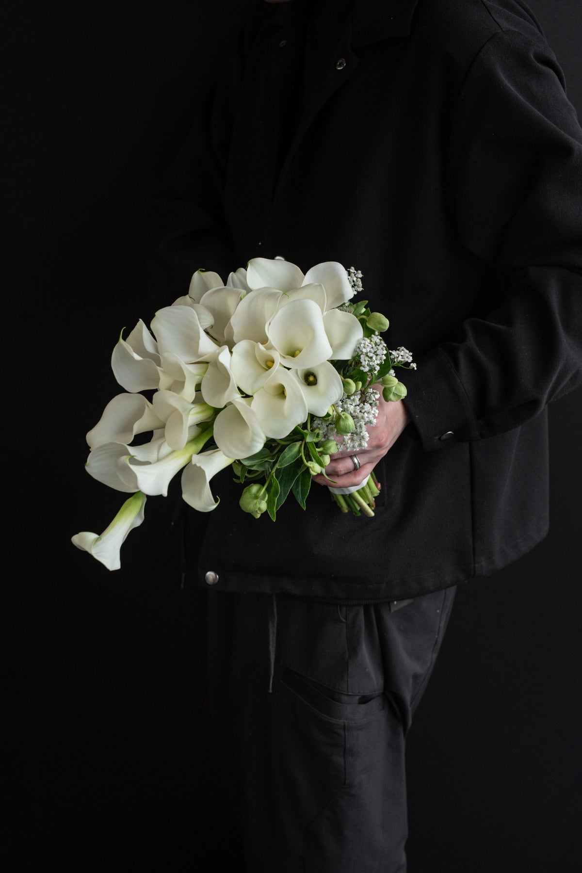 Side view of A Lifetime with You bridal bouquet on a black plinth, showing the cascading waterfall silhouette of white blooms trailing downward