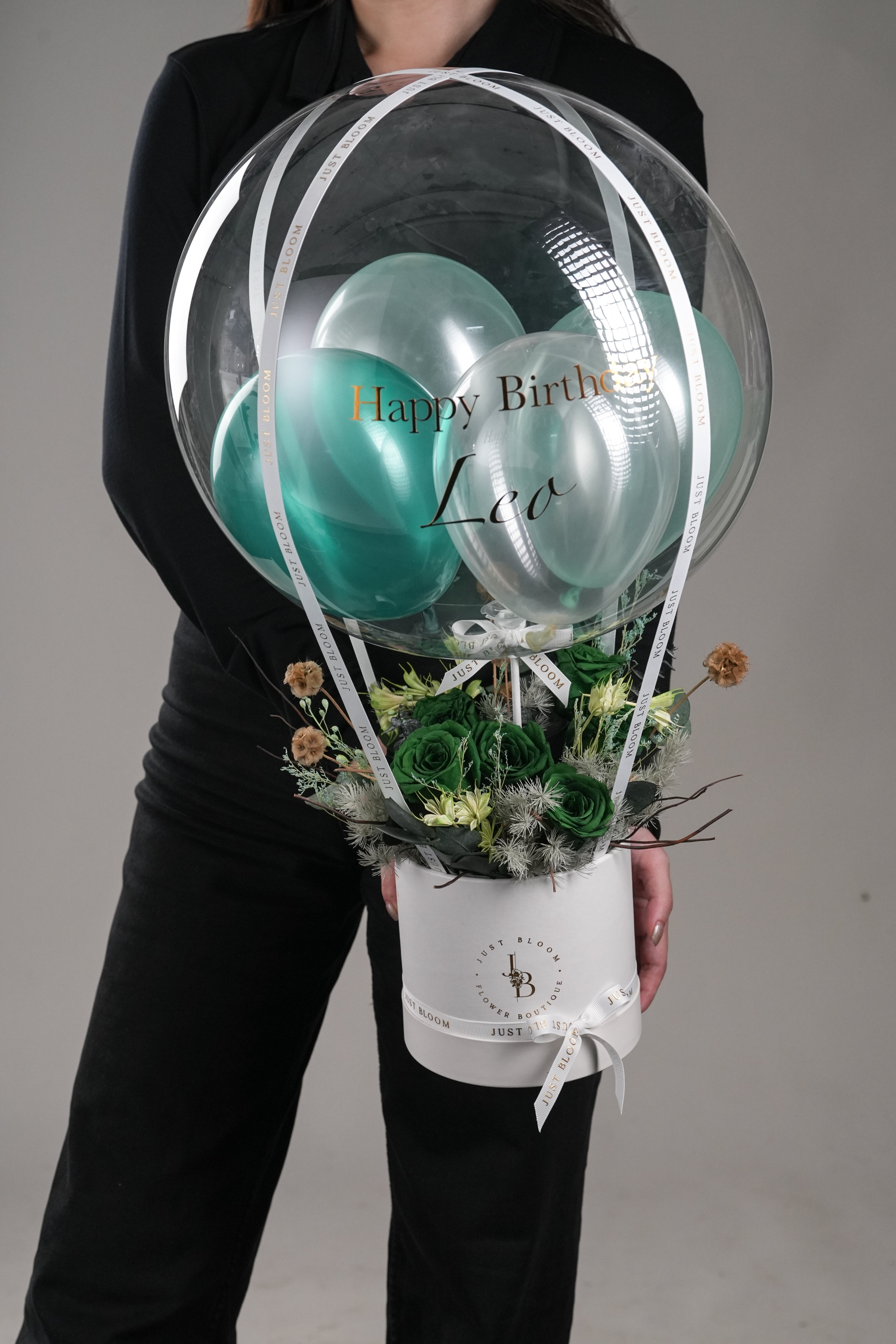 Woman holding Brynn green preserved rose hot air balloon box with white round base