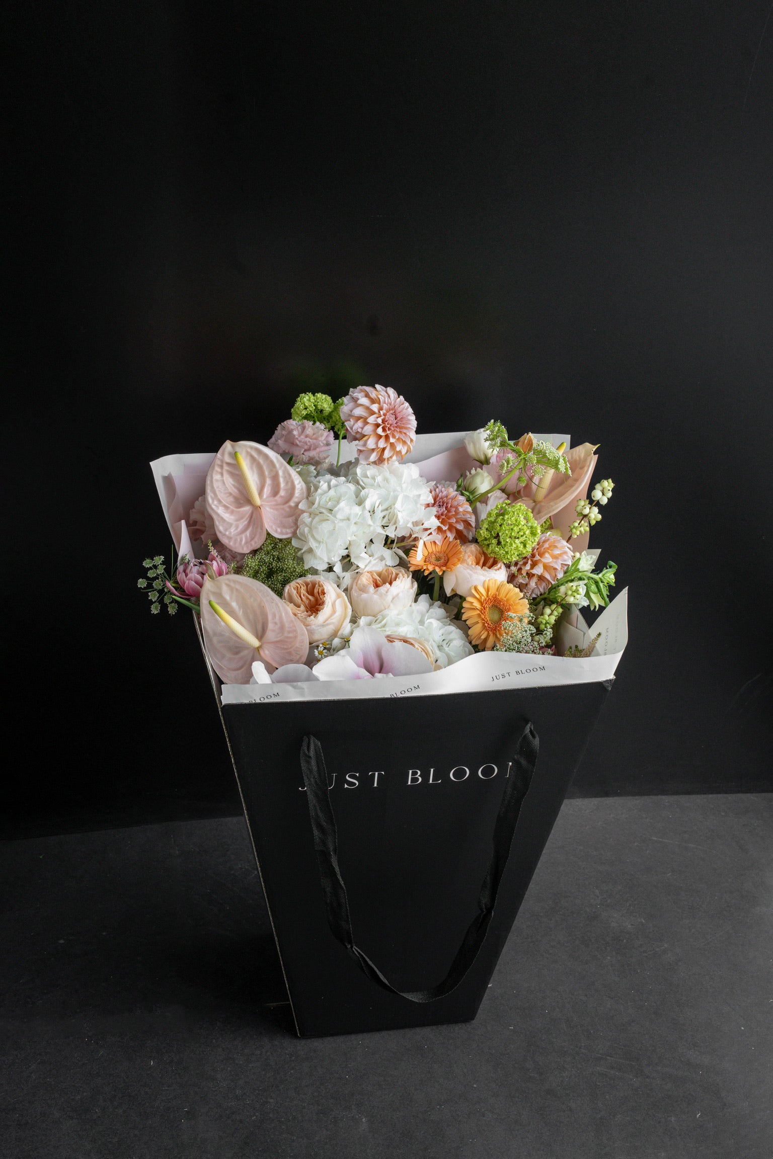 Apricot Garden bouquet displayed inside a black Just Bloom gift bag against a black studio backdrop — Just Bloom Hong Kong