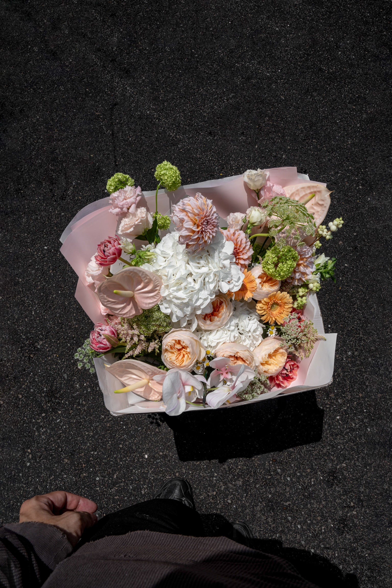 Overhead view of the Apricot Garden bouquet held against dark pavement — Just Bloom Hong Kong