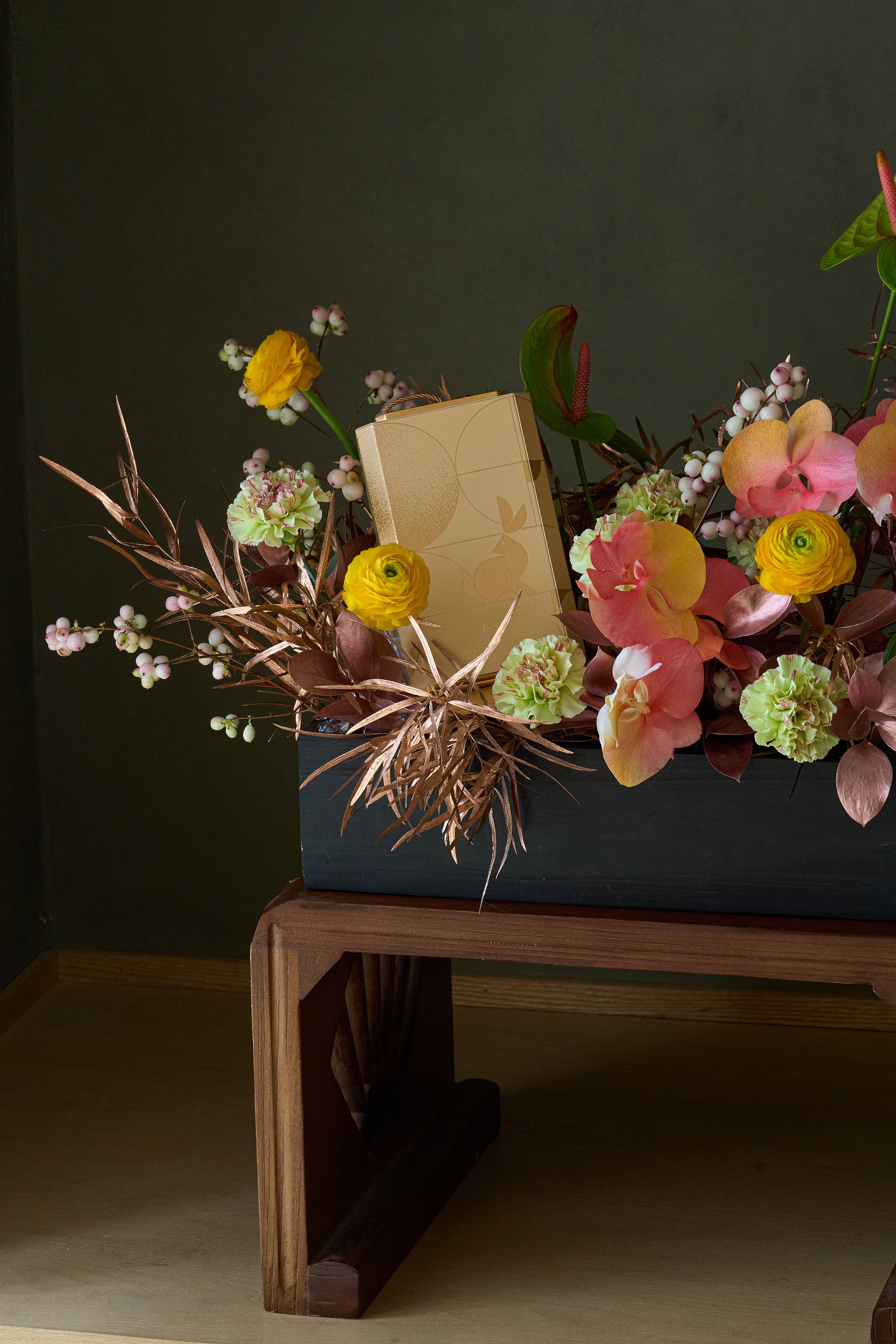 Close-up of golden yellow and coral flower box arrangement with bronze foliage and chocolate gift box — Just Bloom Hong Kong