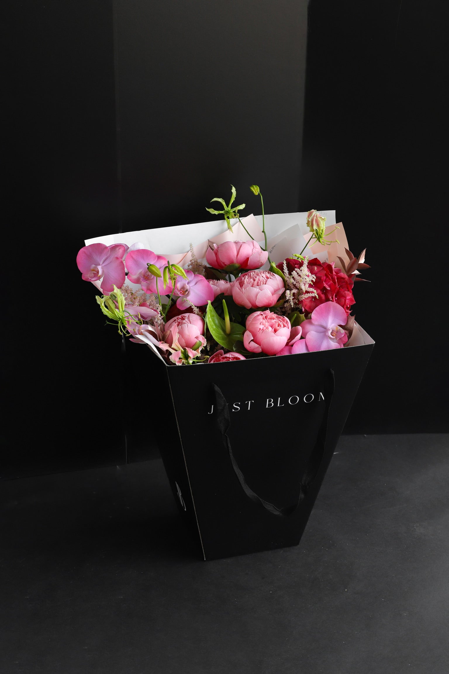 The Bloom Theory luxury bouquet by Just Bloom Hong Kong presented in a black Just Bloom tote bag, showcasing pink peonies, orchids and astilbes