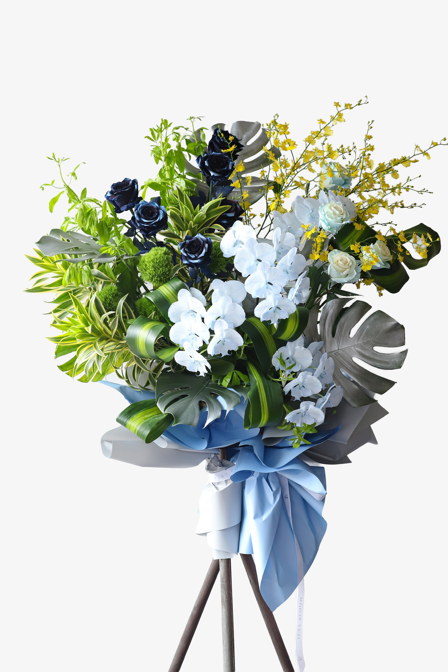 A large luxury flower stand in powder blue wrapping featuring deep navy roses, white phalaenopsis orchids, yellow winter jasmine and silver monstera leaves — Blue Horizon by Just Bloom Hong Kong