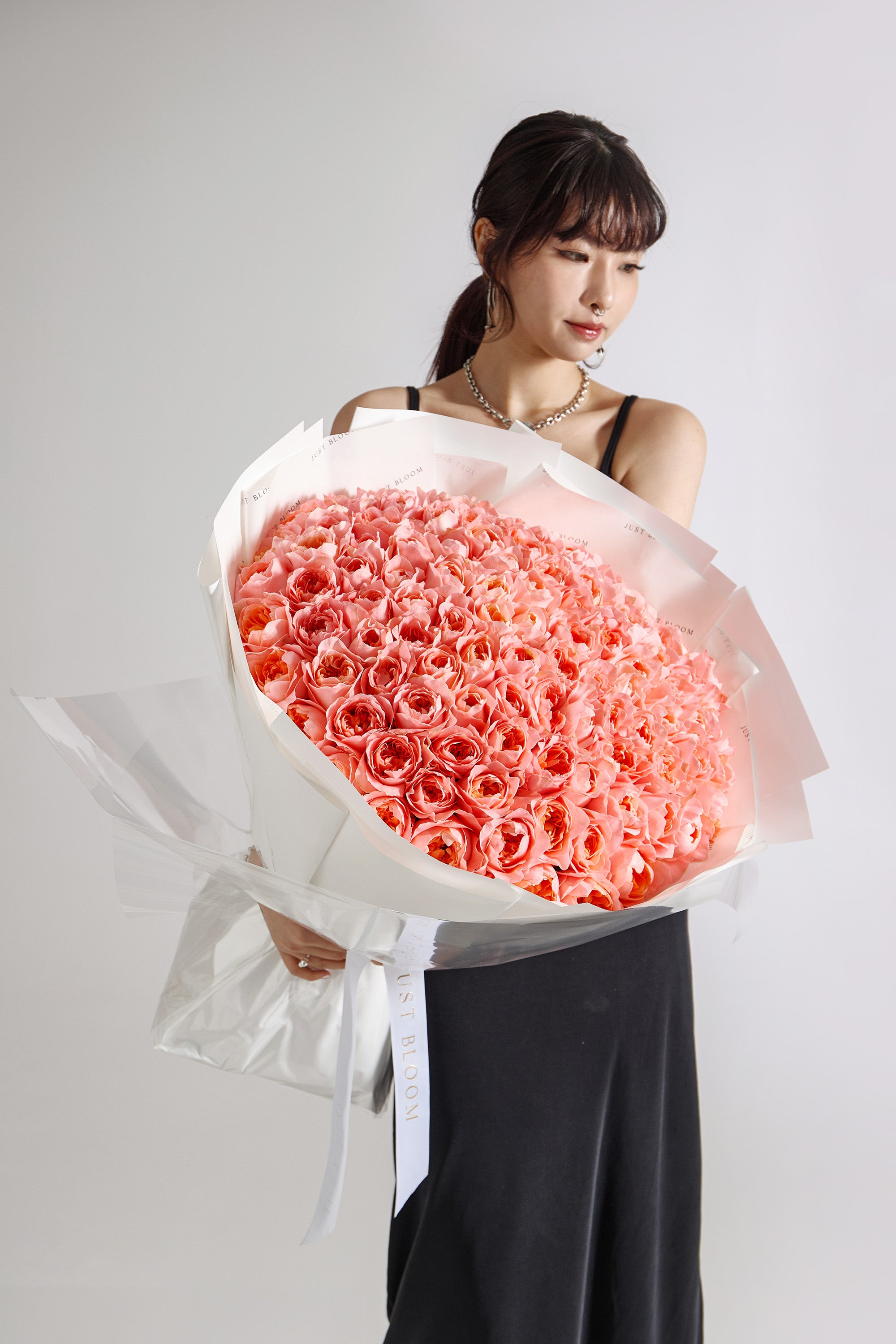 Large luxury bouquet of over 100 pink coral blush roses arranged in dome shape with white and pink wrapping