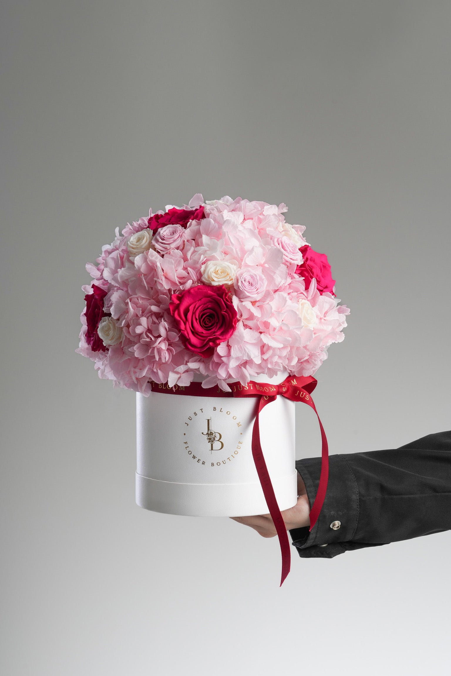 Side view of Calliope preserved rose arrangement with red ribbon