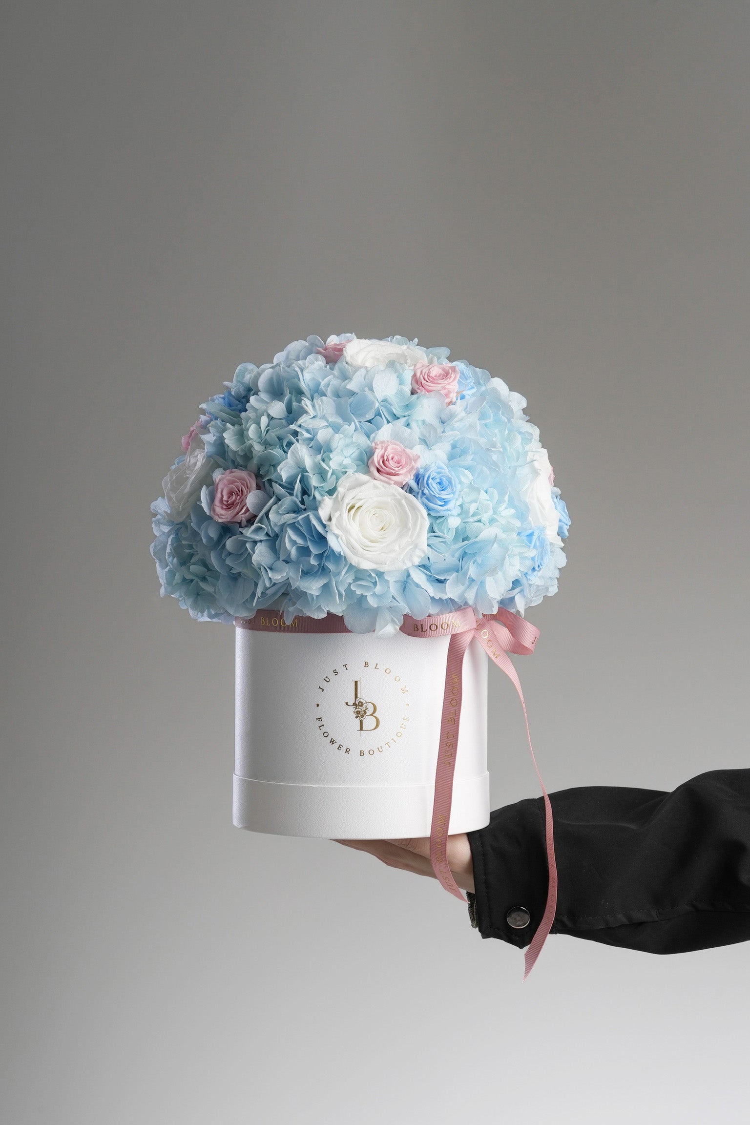 Just Bloom Hong Kong Capri preserved flower box – held in hand against a grey backdrop, showcasing fullness of arrangement
