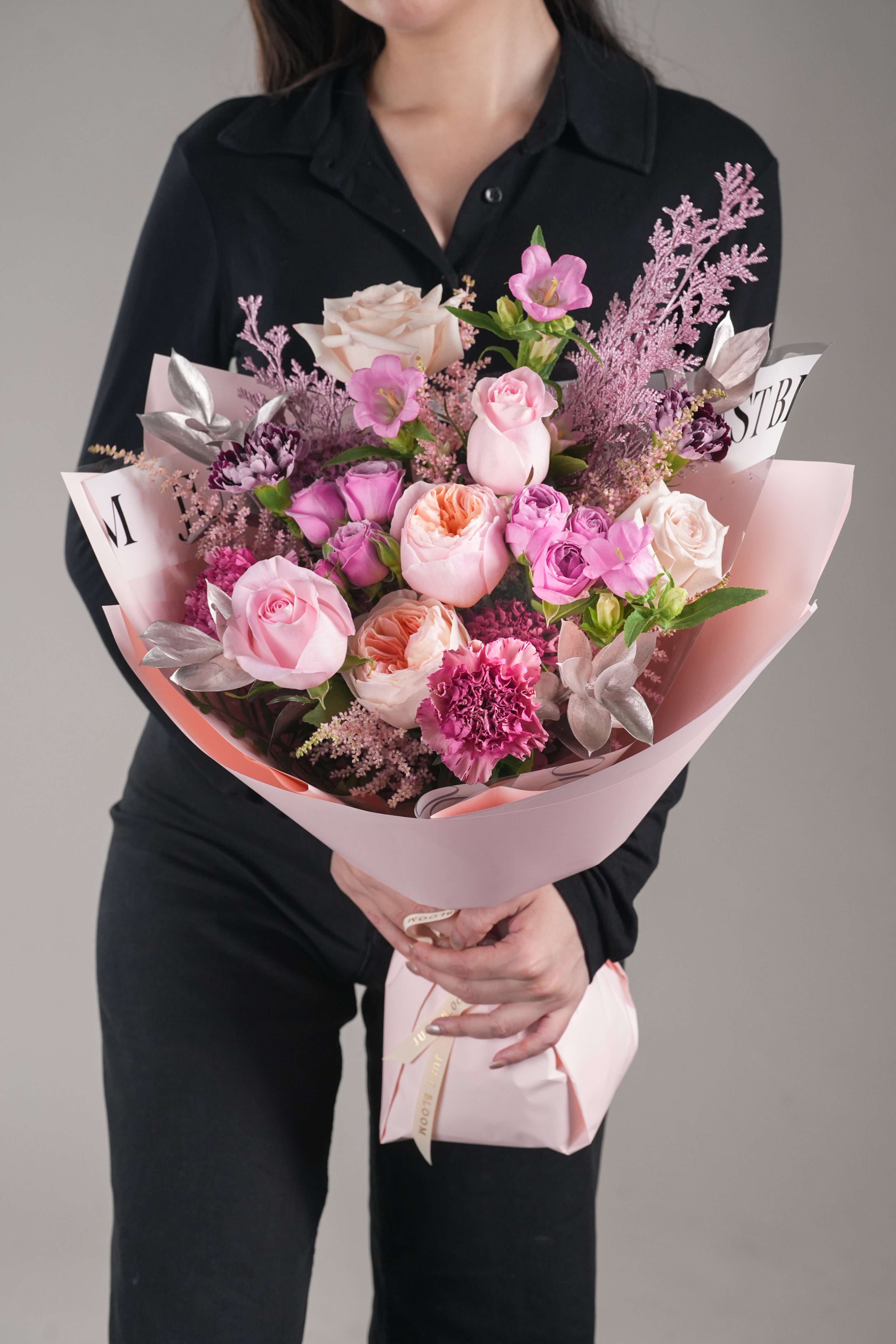 Chelsea romantic Juliet rose bouquet – pink and peach garden roses with carnations and filler flowers wrapped in pink paper.