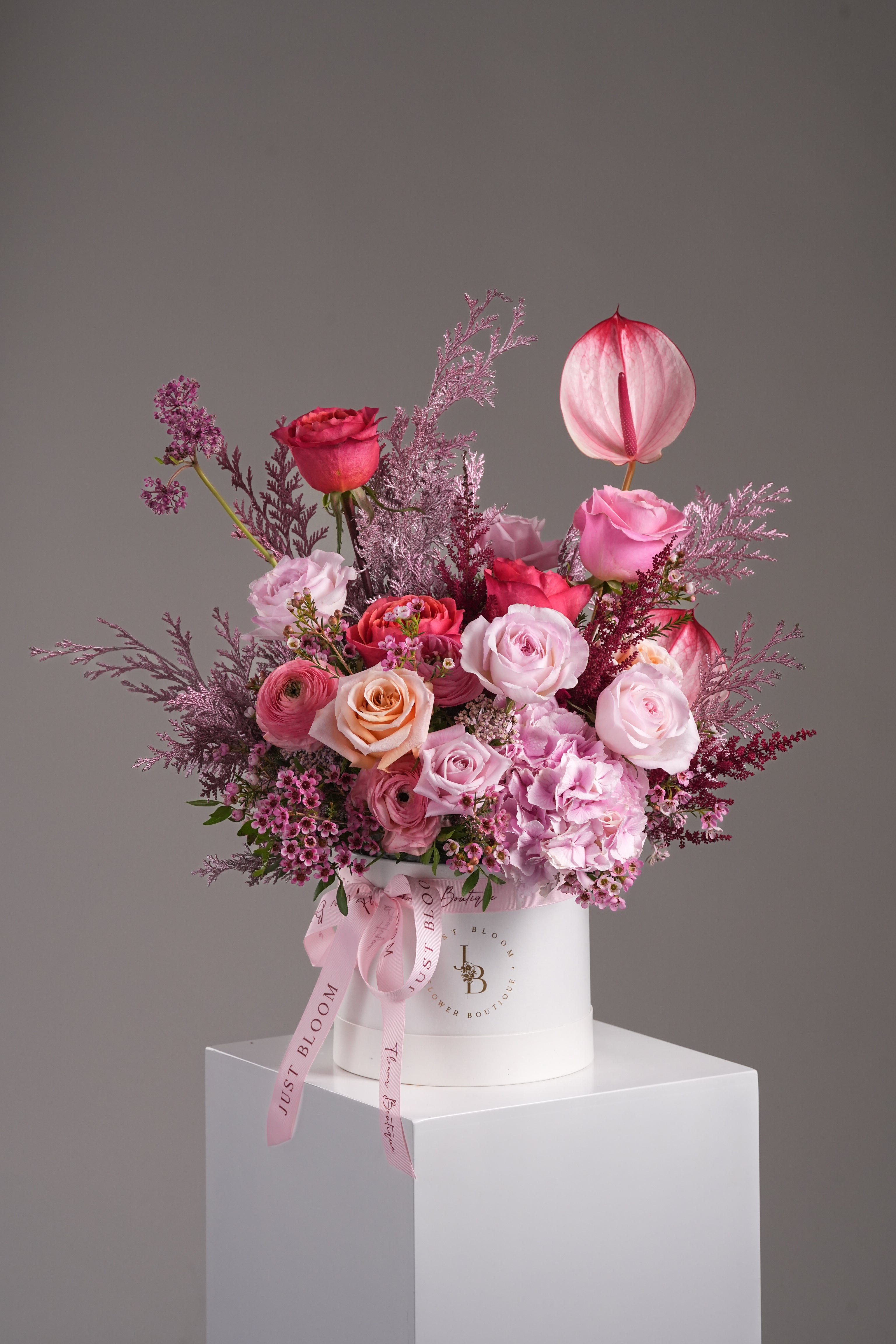 Full frontal image of Coraline flower hatbox in pink tones on pedestal