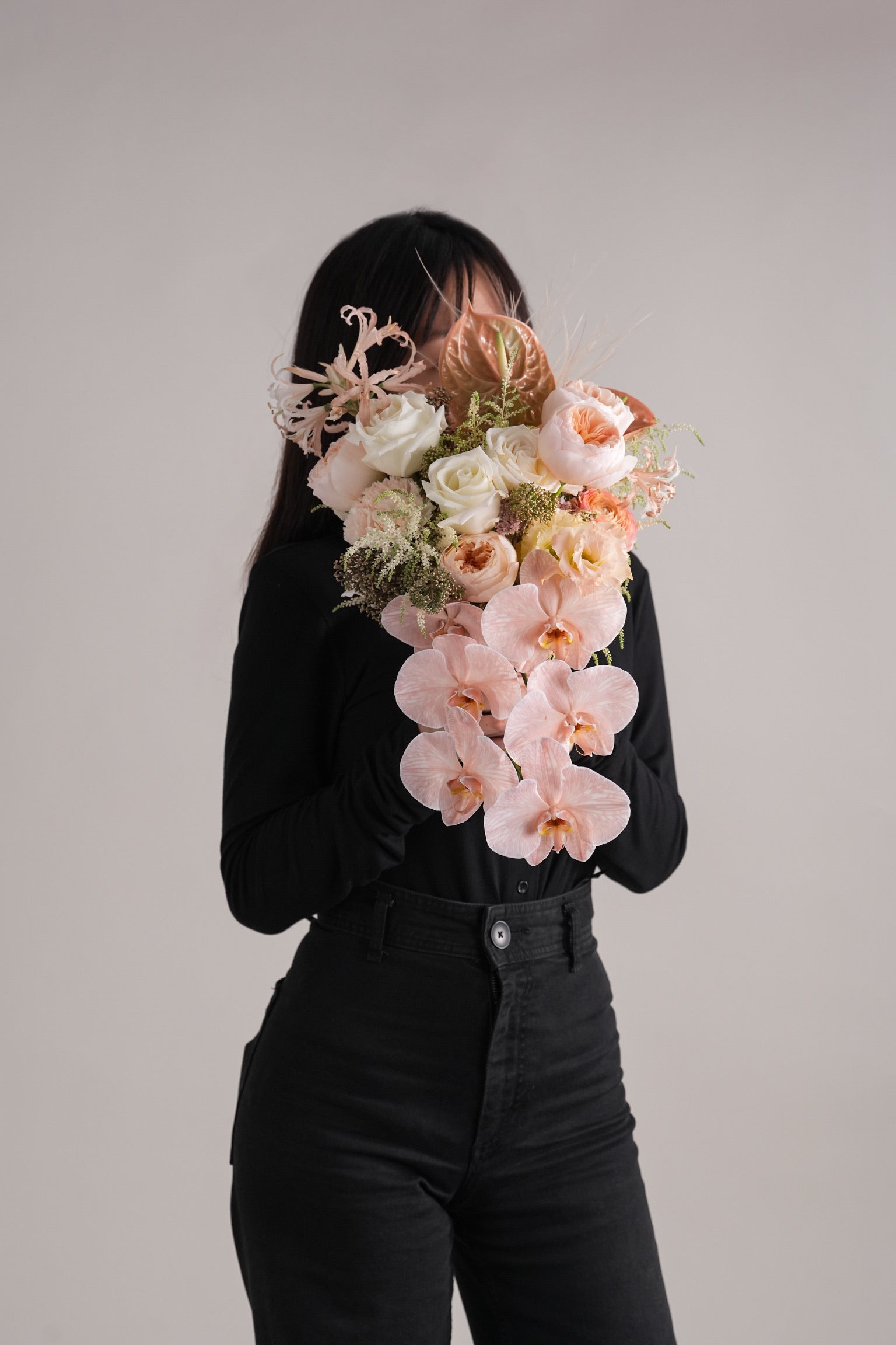 woman holding Davina bridal bouquet with flowing orchids and pastel florals