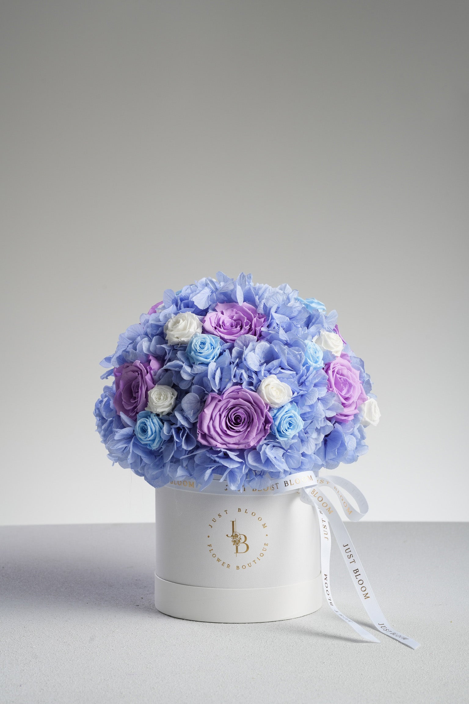 Eileen - A preserved flower box featuring blue hydrangeas, lavender, baby blue, and white roses in a soft colour palette. Elegant floral gift by Just Bloom HK