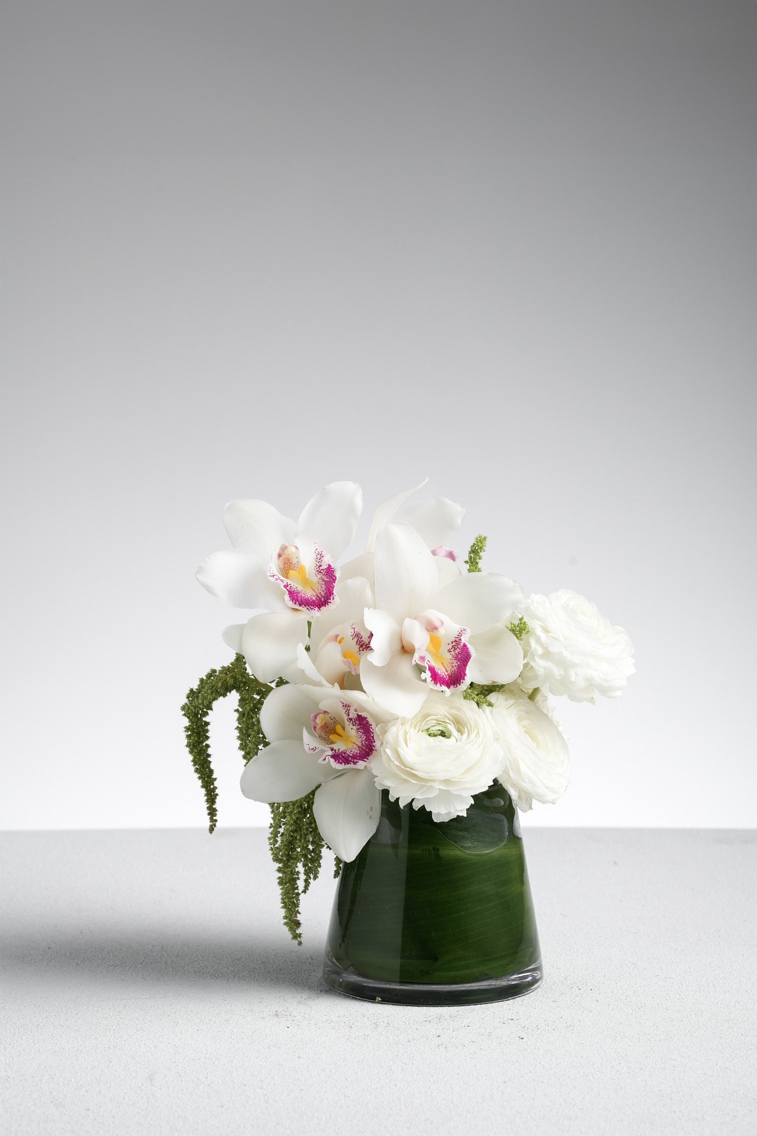Just Bloom Faye mini vase flower arrangement with white cymbidium orchids and ranunculus – front view