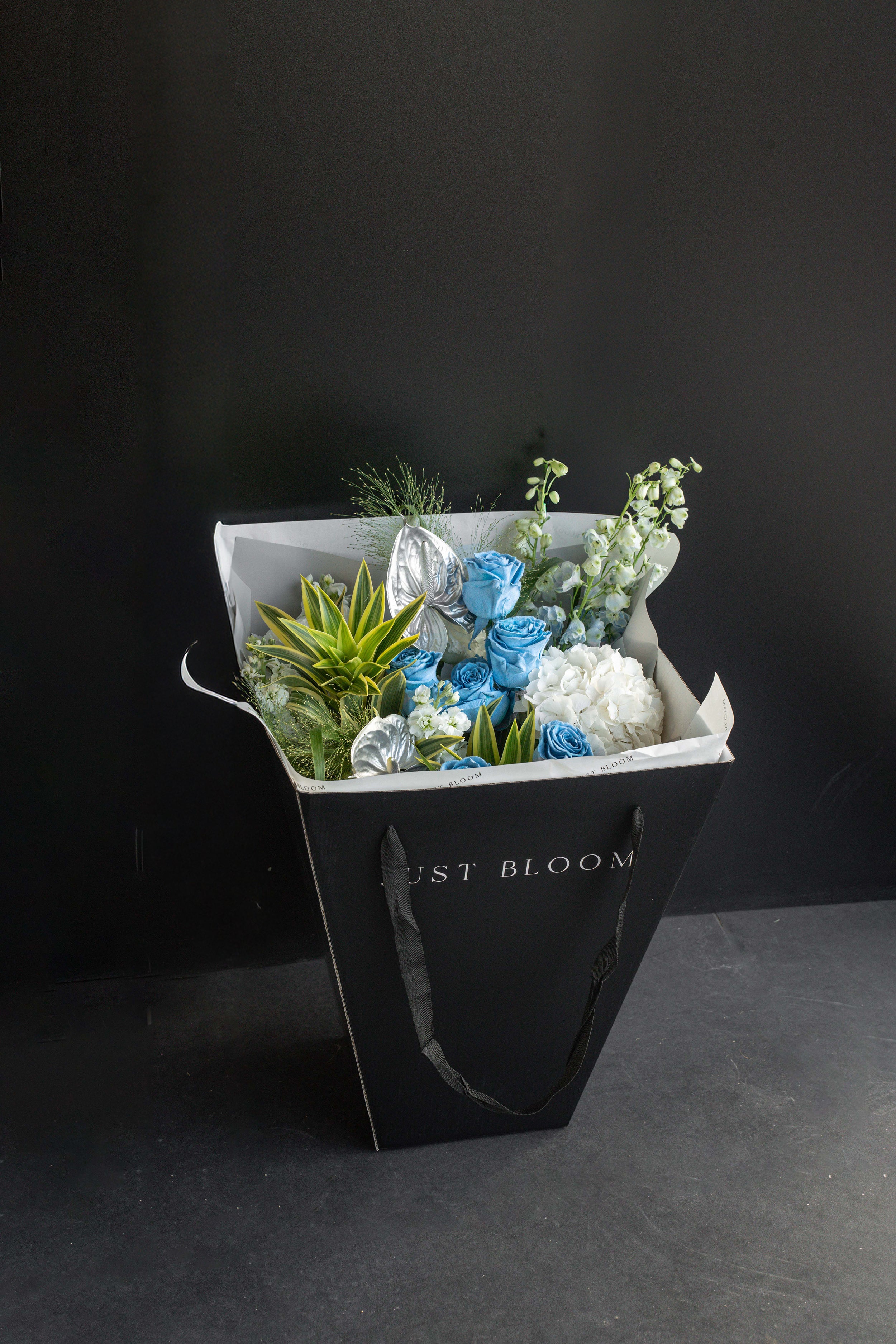 Frost Bloom bouquet displayed inside a black Just Bloom gift bag against a black studio backdrop — Just Bloom Hong Kong