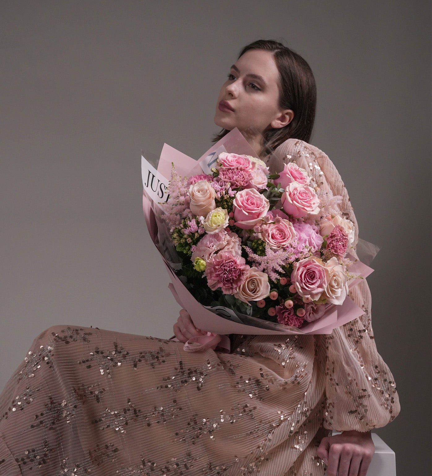 Woman in sequin dress holding Gentle Sweetness pink bouquet by Just Bloom HK, featuring Ecuadorian roses and Dutch flowers