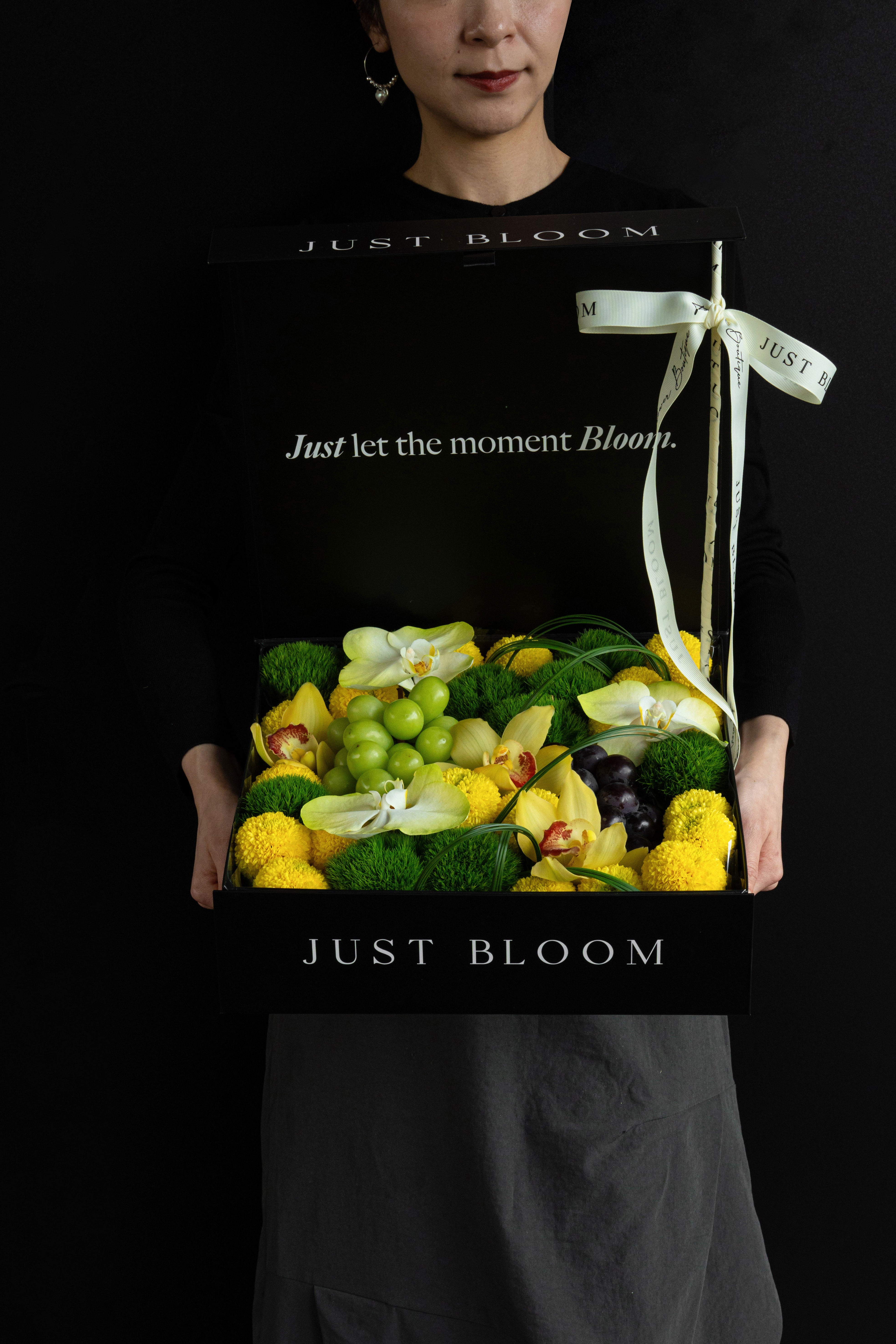Model holding Just Bloom Jade Moon flower box with yellow and green florals and grapes — Just Bloom Hong Kong