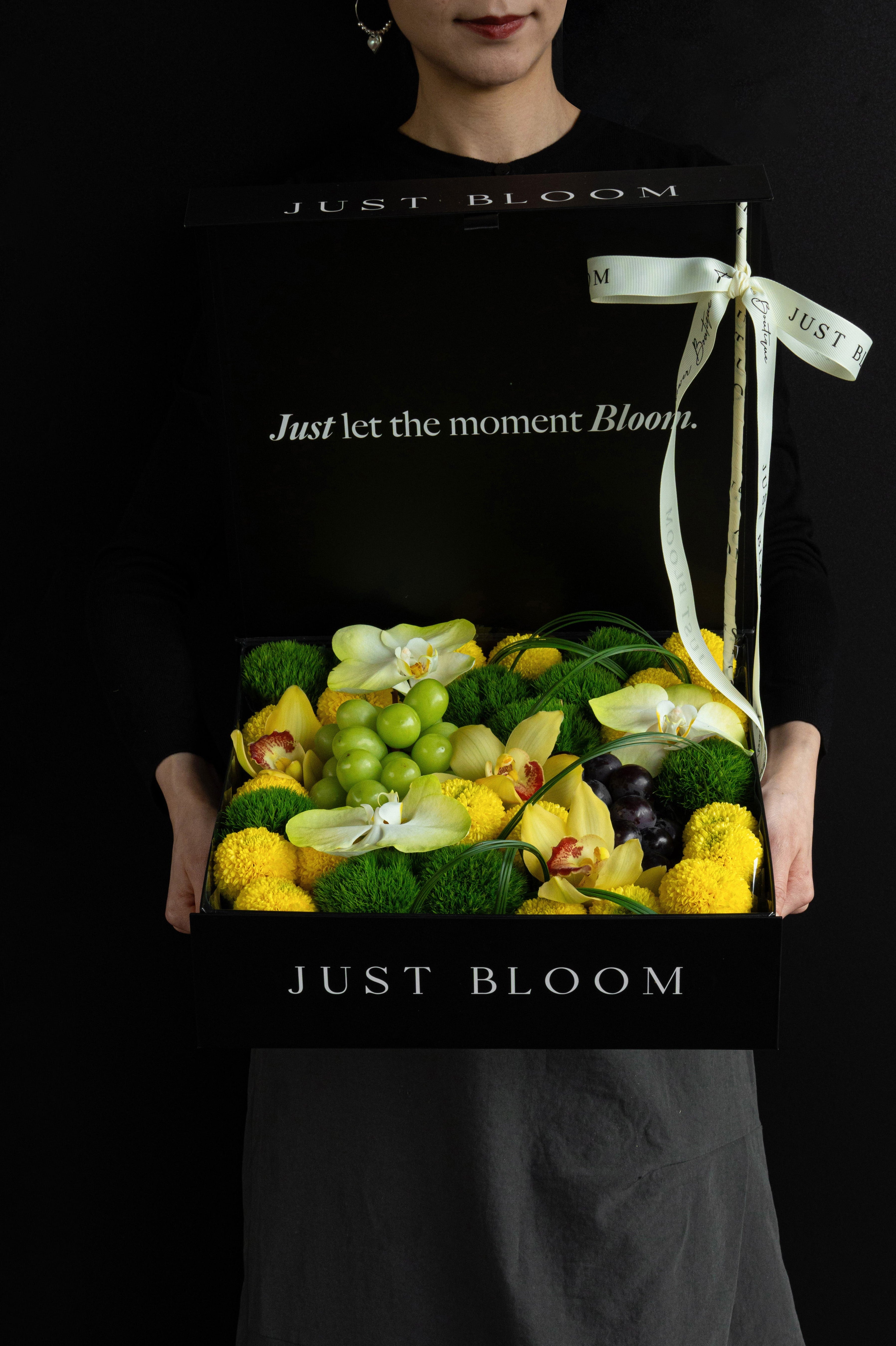 Model holding Just Bloom Jade Moon flower box with yellow and green florals and grapes — Just Bloom Hong Kong