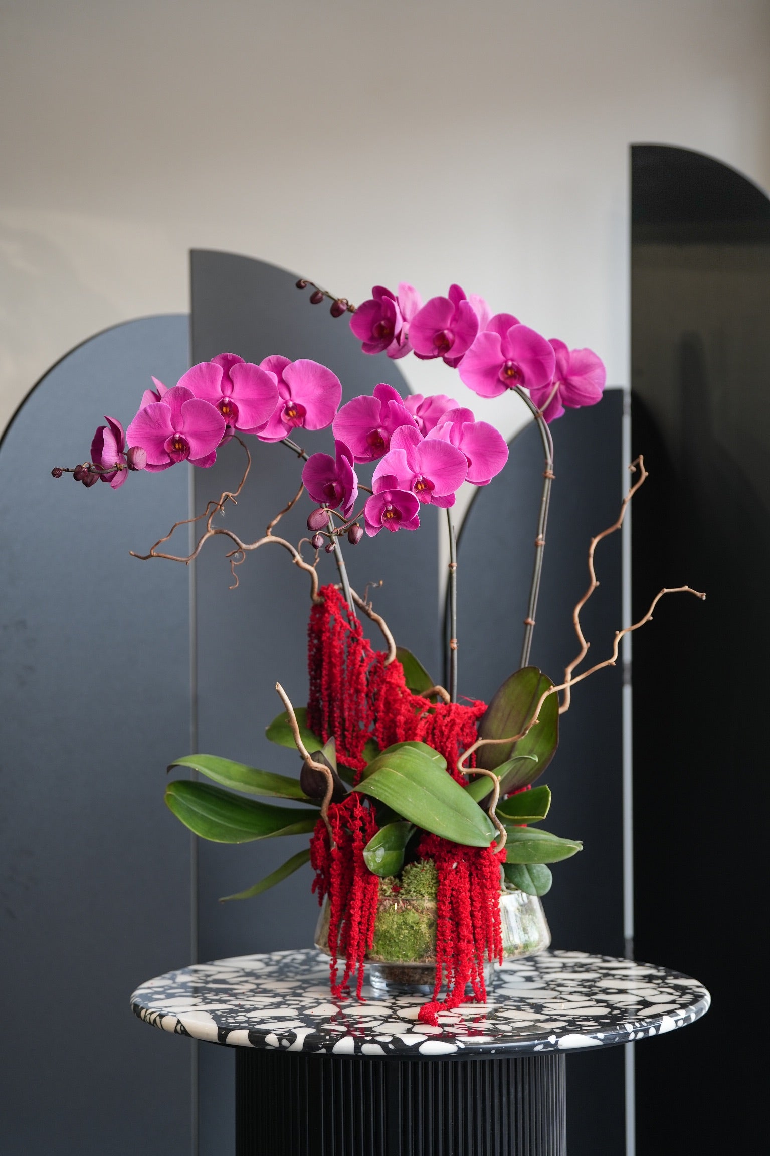 Cecelia orchid flower arrangement on black marble table with pink Phalaenopsis and red amaranthus