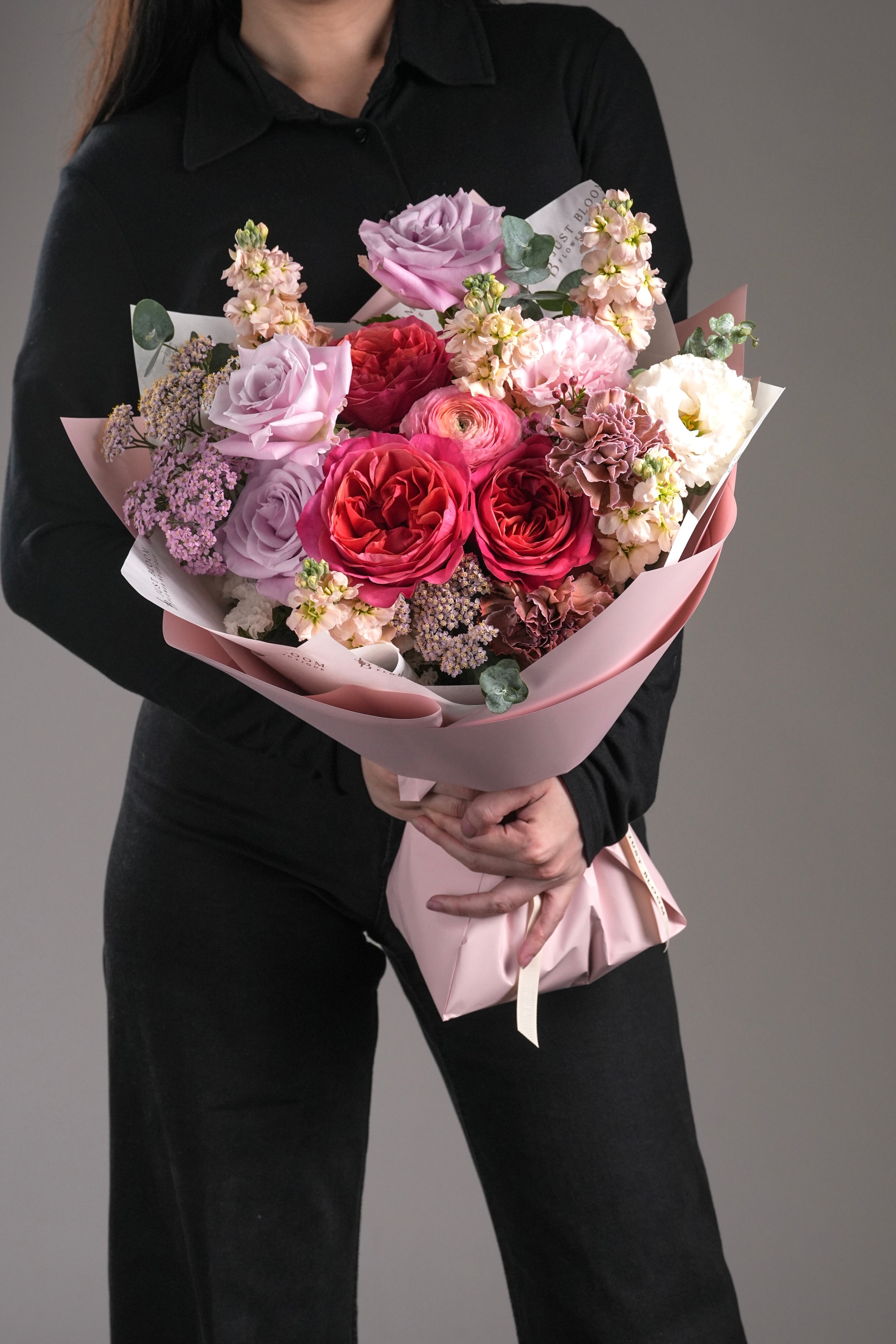 Celia bouquet held by model – vibrant pink and peach rose bouquet with lilac fillers