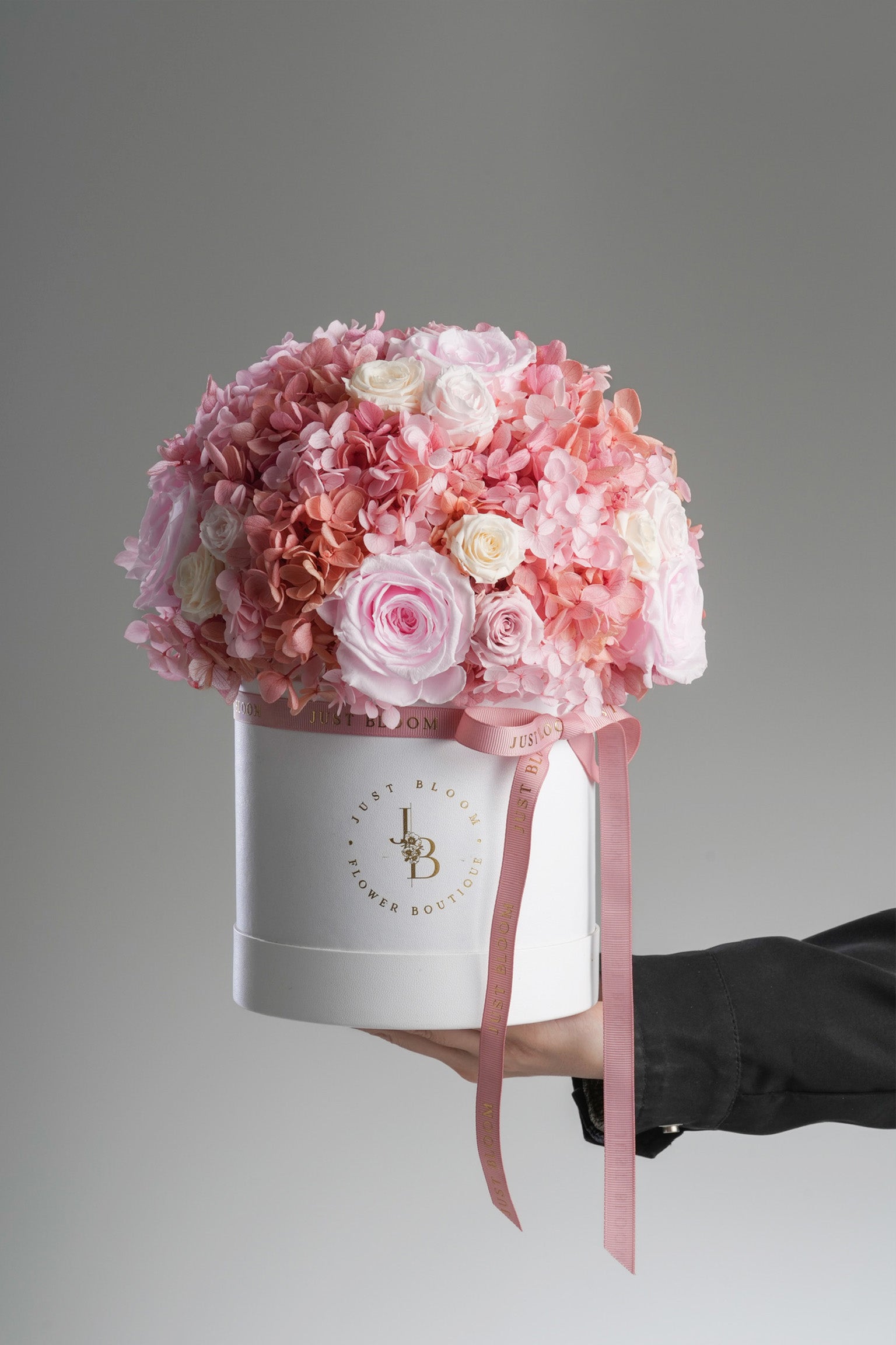Hand holding Kyra preserved flower box showing scale and elegant white hatbox design