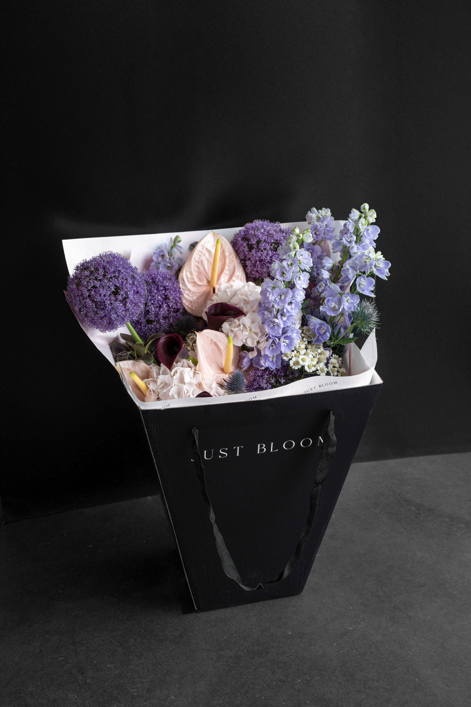 Lavender Muse bouquet displayed inside a black Just Bloom gift bag against a black studio backdrop — Just Bloom Hong Kong