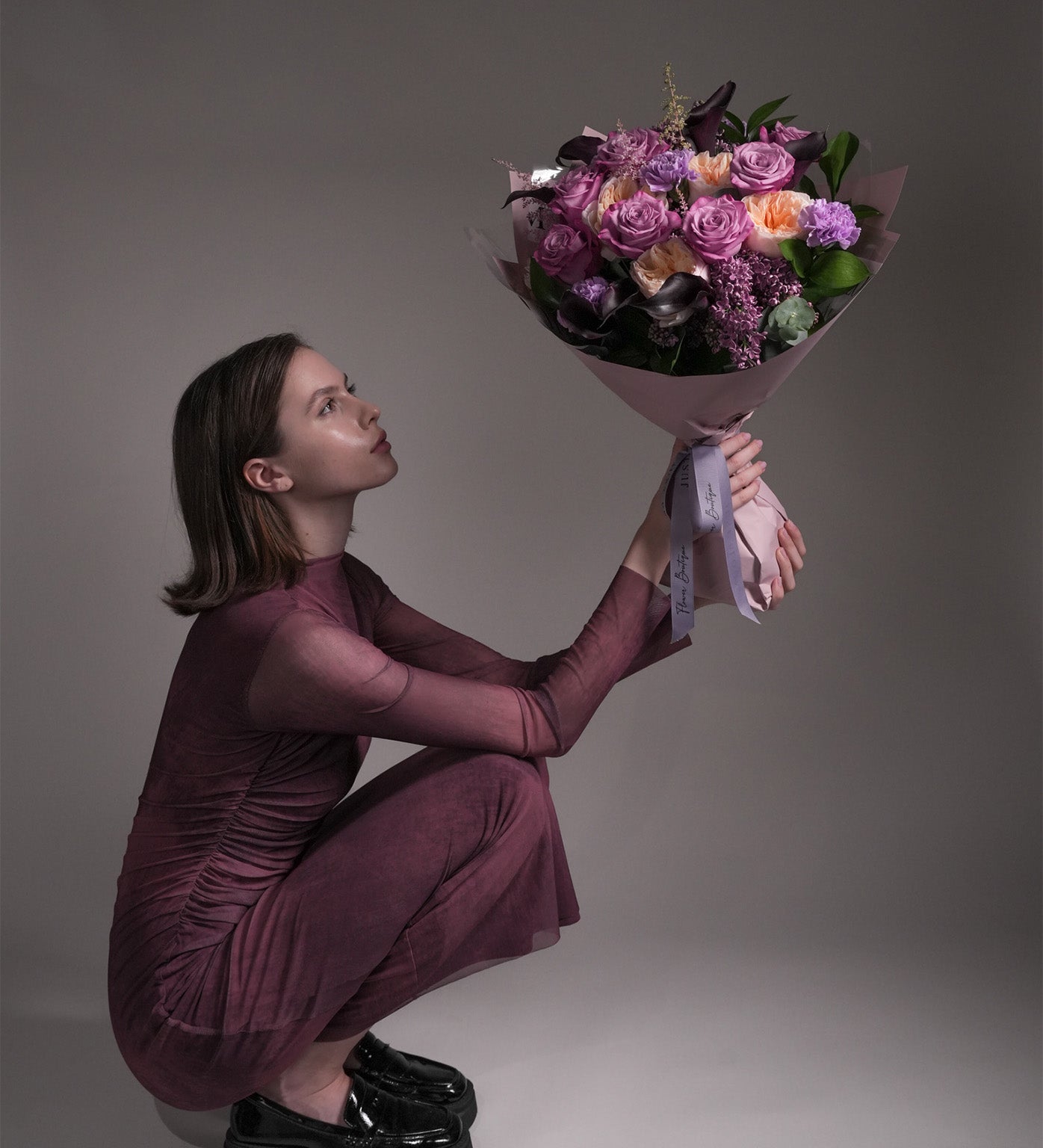 Model holding Maternal Grace purple and lavender bouquet with roses, Juliet garden roses, and astilbes