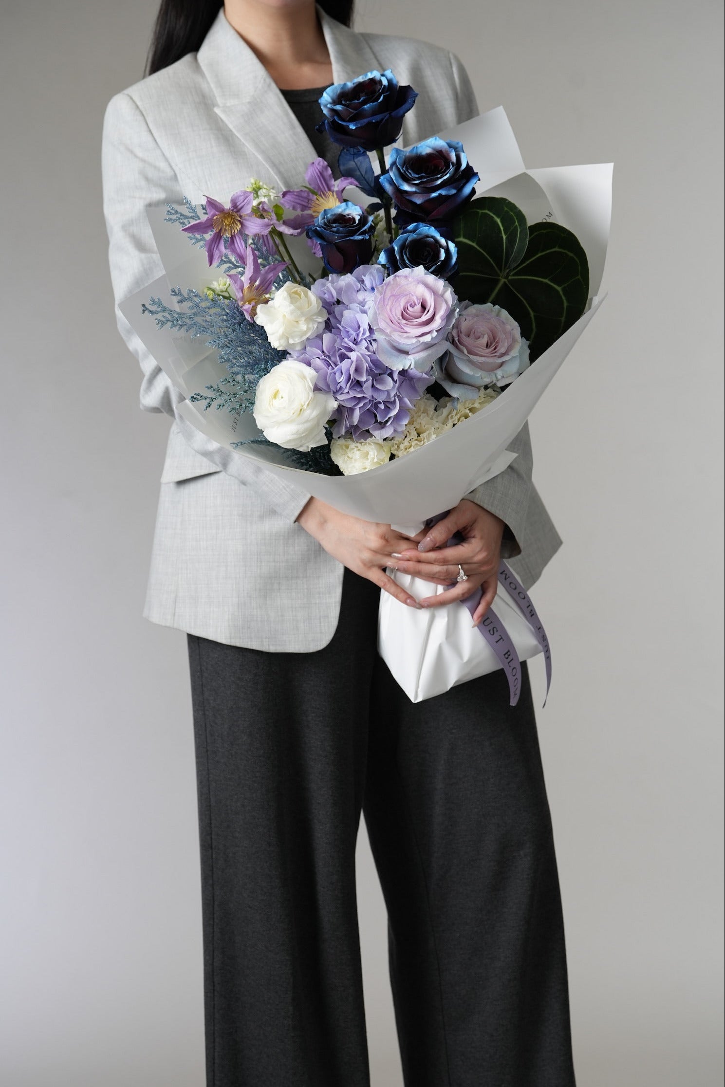 Noctis bouquet with blue roses, lilac roses and hydrangeas held in front view