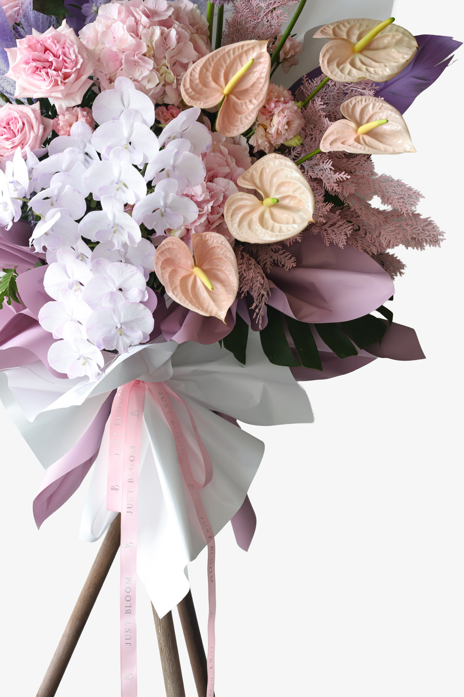 Close-up of Petal Cloud flower stand by Just Bloom Hong Kong showing peach anthuriums, white phalaenopsis orchids, pink hydrangeas and carnations with mauve wrapping and Just Bloom ribbon
