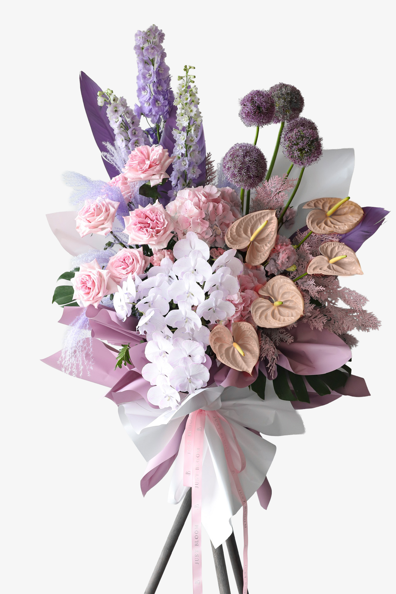 A luxury flower stand in mauve and white wrapping featuring white orchids, peach anthuriums, lavender delphiniums and giant alliums — Petal Cloud by Just Bloom Hong Kong