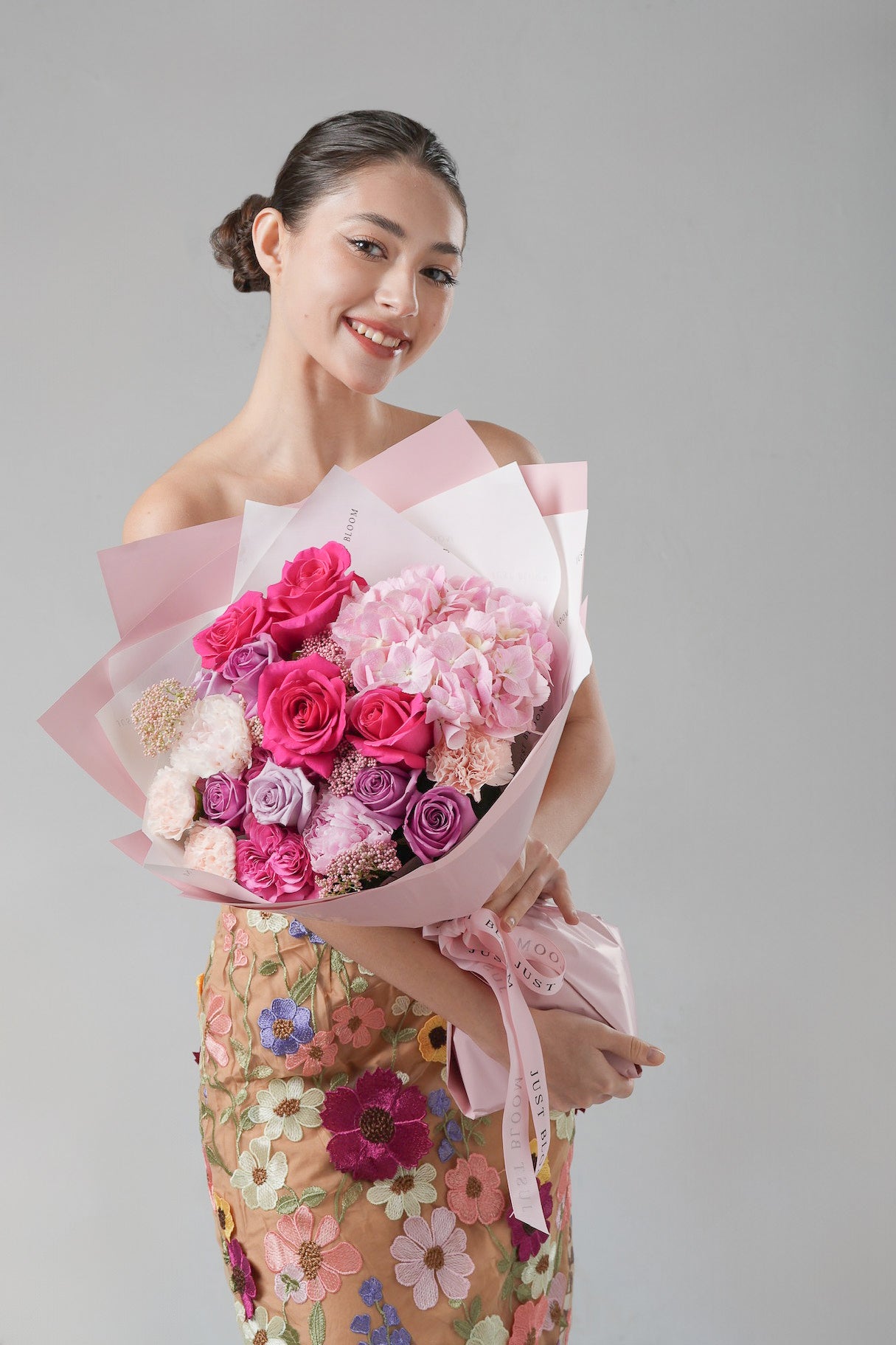 A bold and elegant bouquet featuring fuchsia roses, lavender garden roses, pink hydrangeas, and peonies in soft pastel tones.