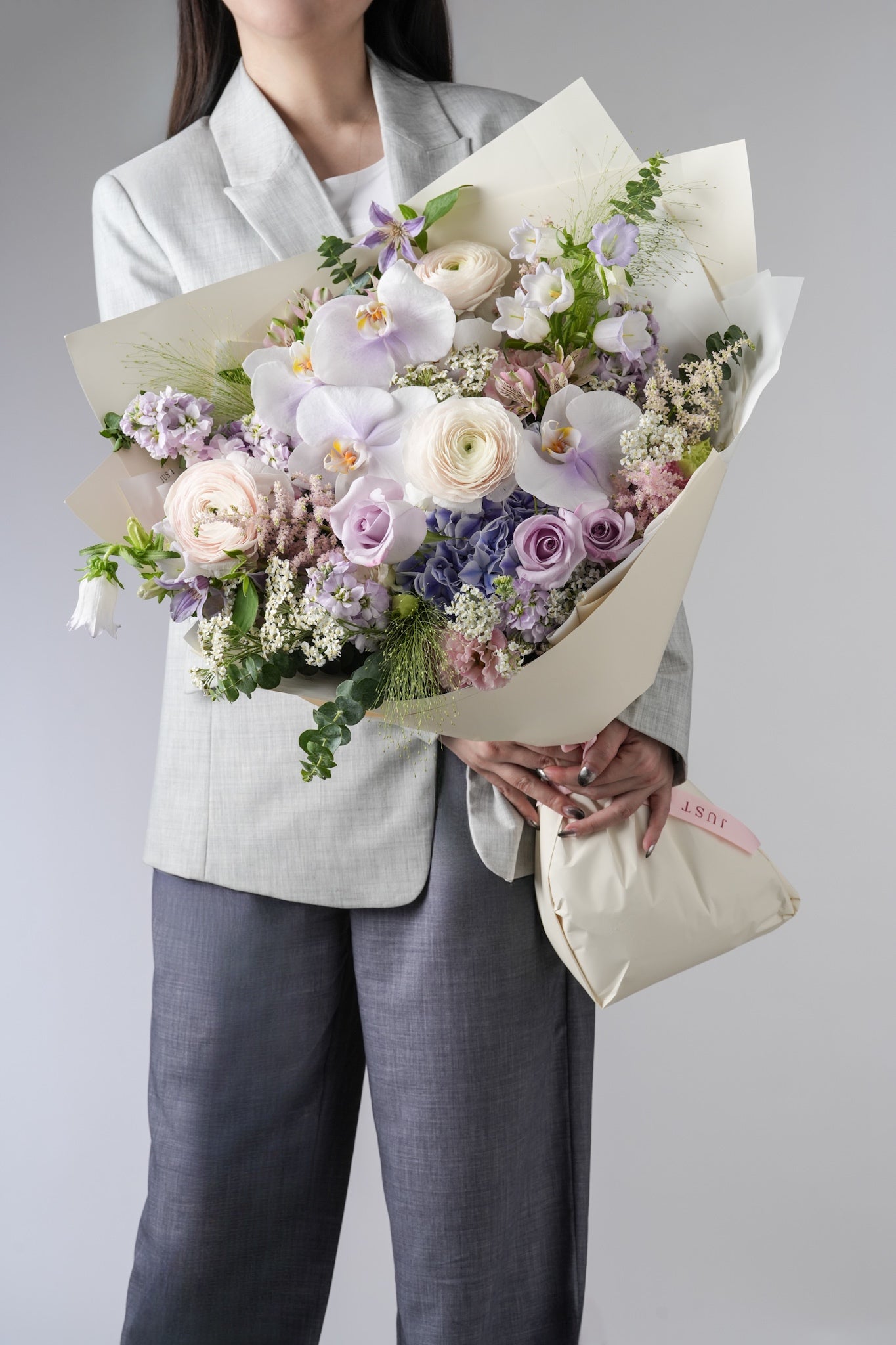 Sandra bouquet with pastel purple orchids, roses, ranunculus, hydrangeas and greenery