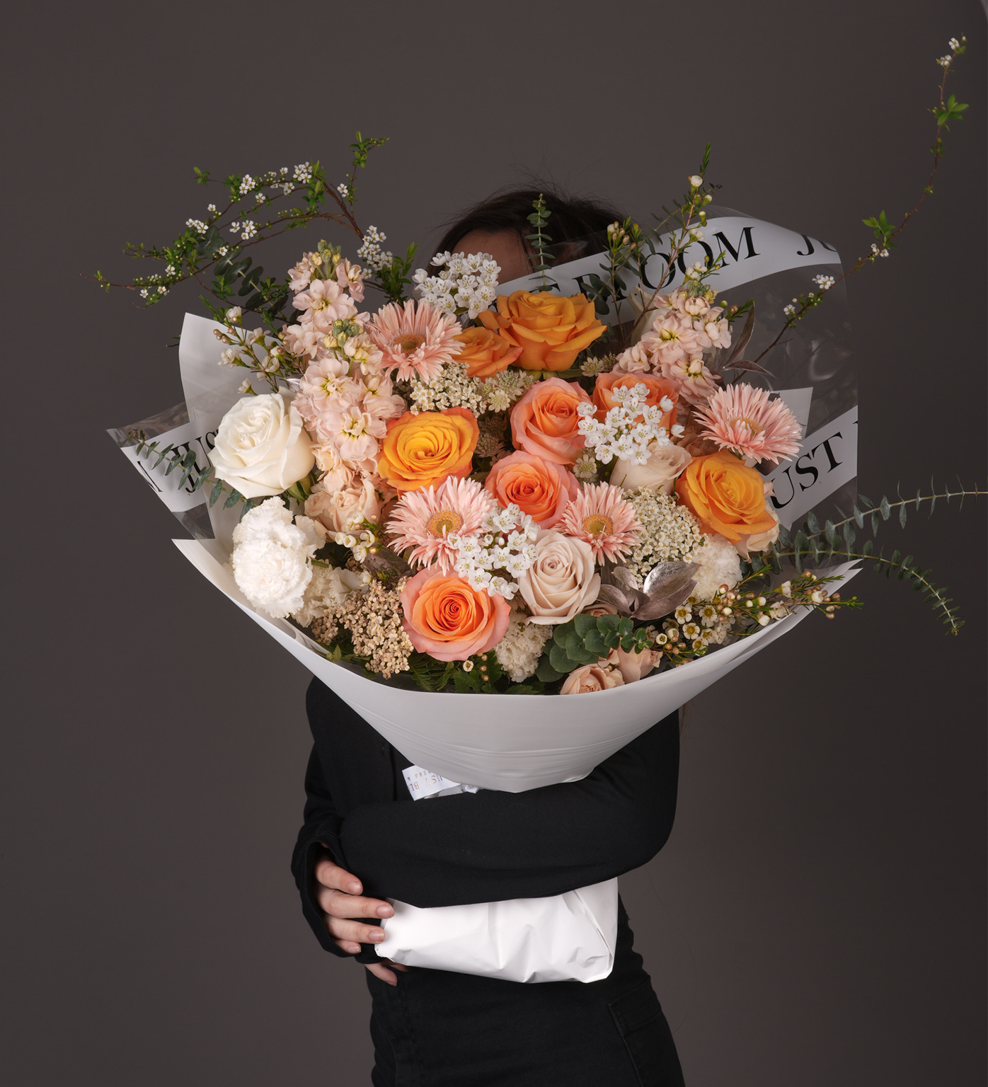 Sierra bouquet with Ecuadorian roses in peach, coral and orange tones, gerberas, spray roses, and eustomas with eucalyptus greenery