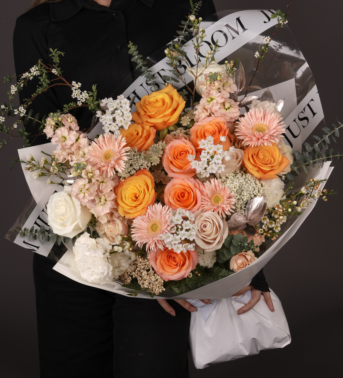 Sierra bouquet with Ecuadorian roses in peach, coral and orange tones, gerberas, spray roses, and eustomas with eucalyptus greenery