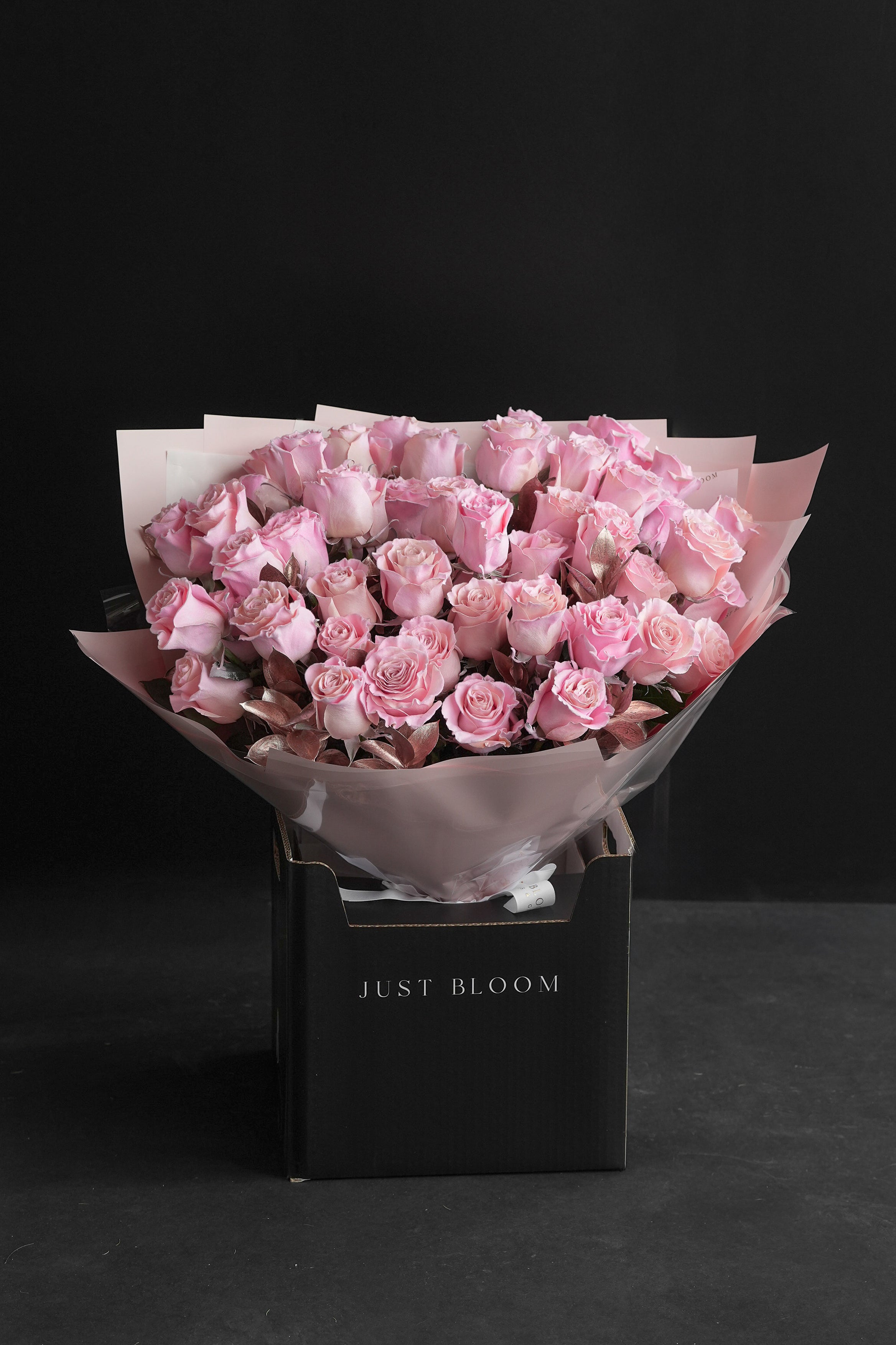Full Soft Flush blush rose bouquet wrapped in pink paper, displayed in a black Just Bloom box against a black studio backdrop — Just Bloom Hong Kong
