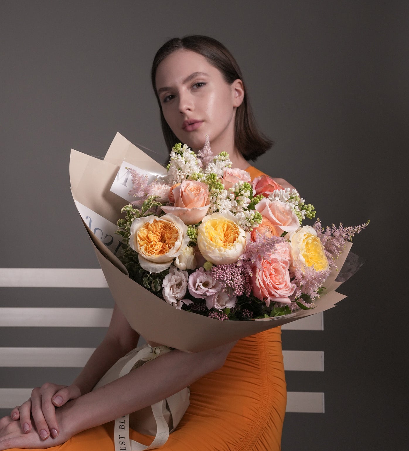 Spring Serenade pastel bouquet with pink, peach, and yellow roses mixed with eustomas and ranunculus