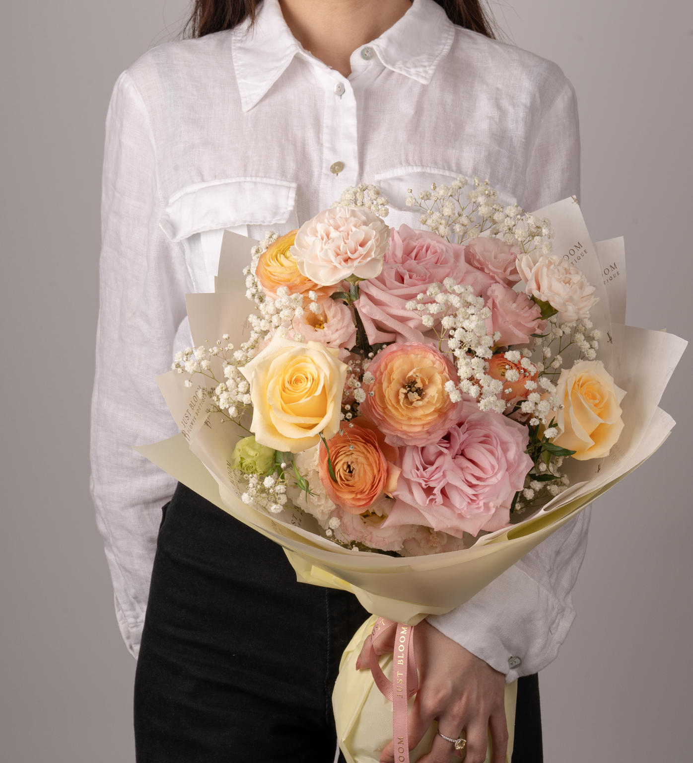 Stevie bouquet with orange, pink and yellow roses, ranunculus, carnations, and baby’s breath