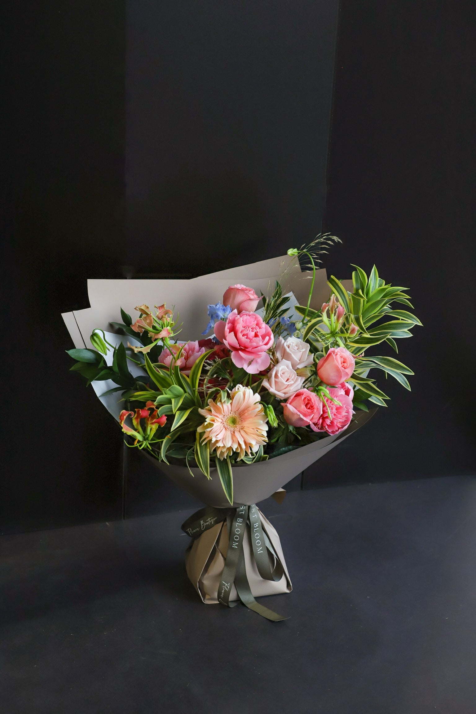 The Botanist luxury bouquet by Just Bloom Hong Kong featuring peonies, roses, gerberas and flame lilies with lush tropical spider plant foliage in taupe wrapping with Just Bloom olive ribbon