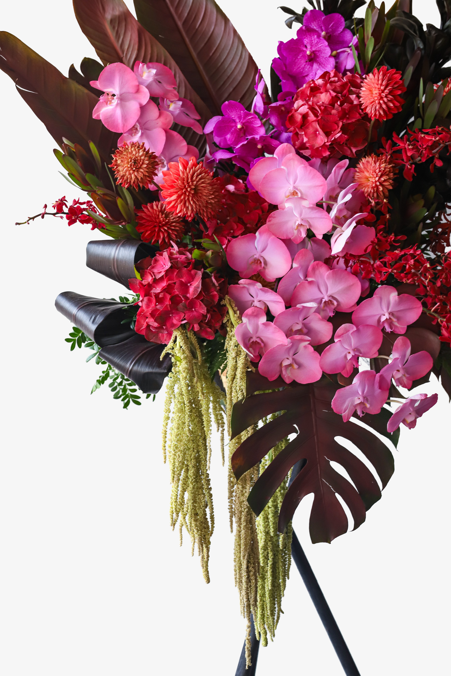 Close-up of Tropical Fire flower stand by Just Bloom Hong Kong featuring pink phalaenopsis orchids, deep red hydrangeas and cascading lime green fillers with dark monstera leaves