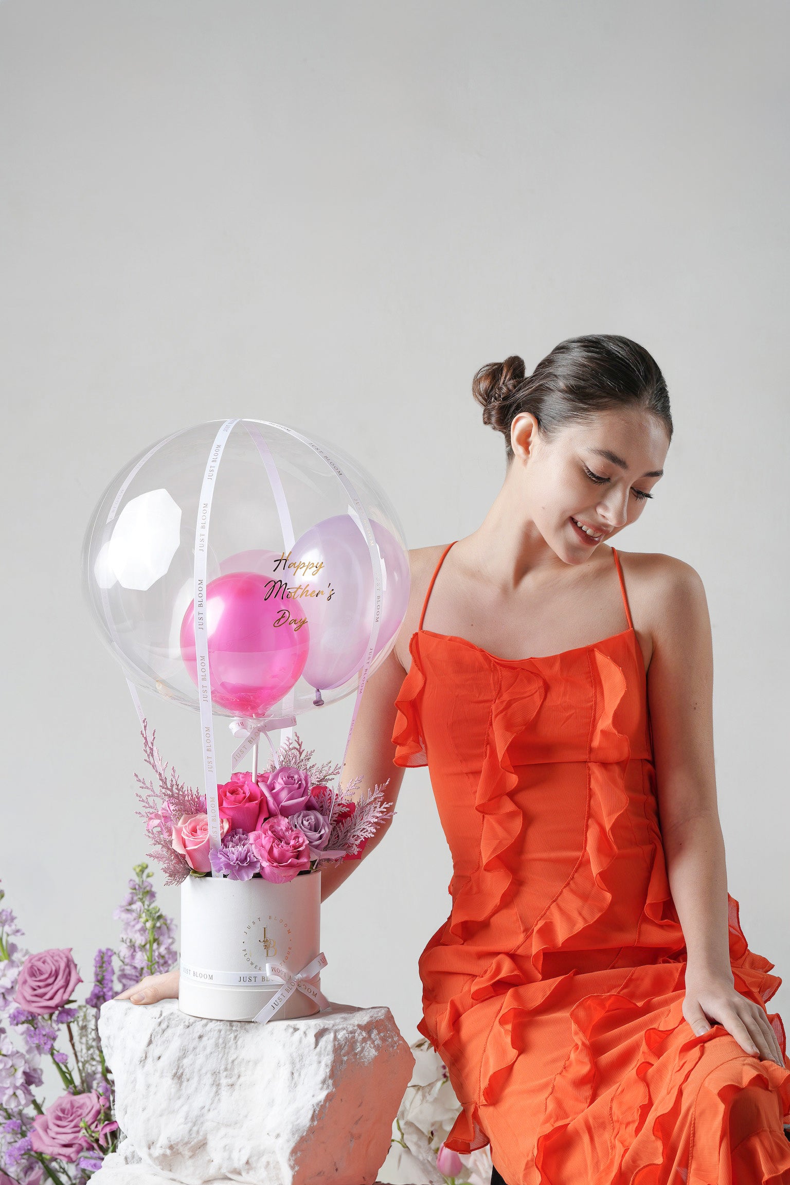 A cheerful floral gift box with pink and purple roses, seasonal fillers, and a decorative crystal balloon.