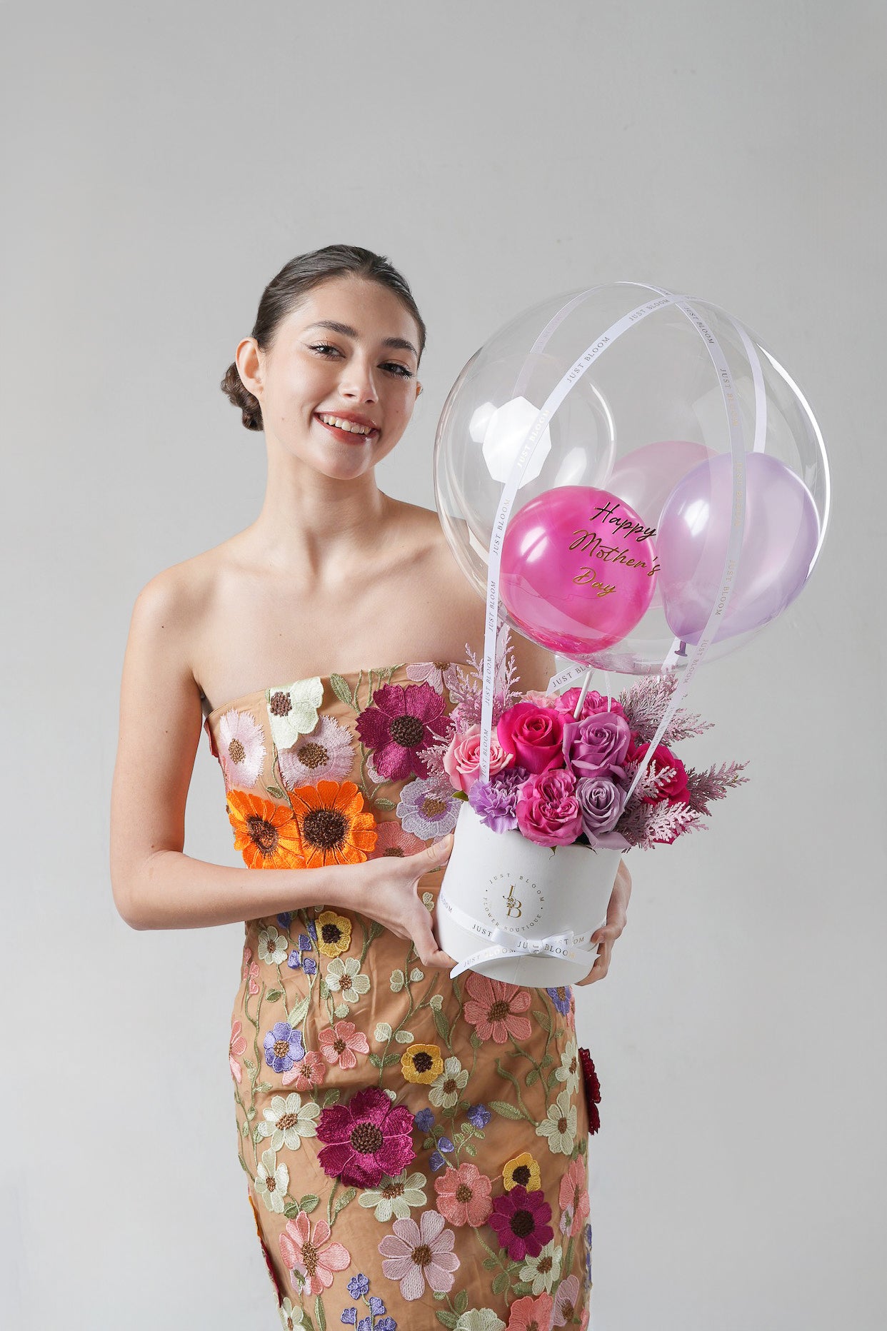 A cheerful floral gift box with pink and purple roses, seasonal fillers, and a decorative crystal balloon.
