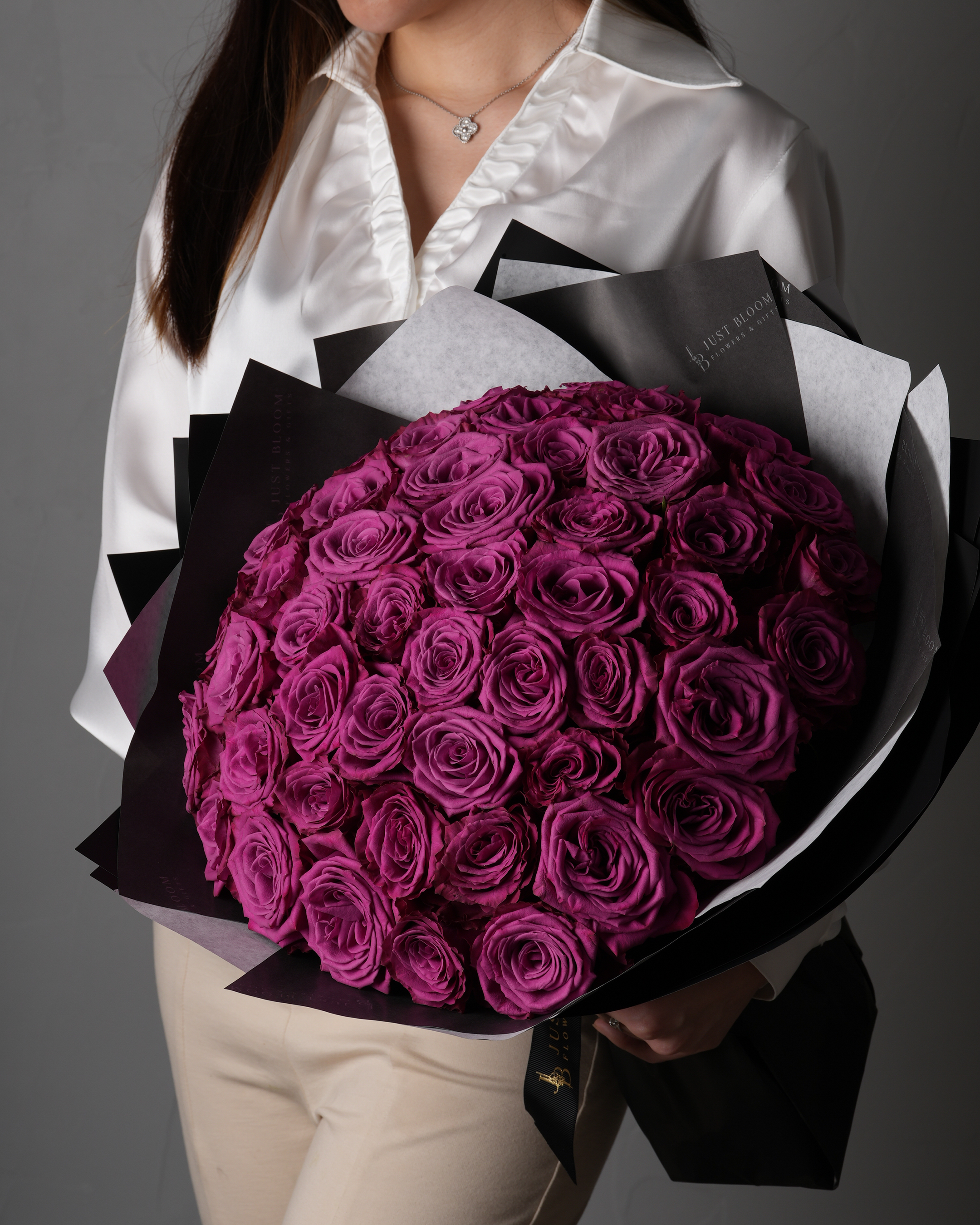 Woman holding a large bouquet of luxury purple roses from Just Bloom