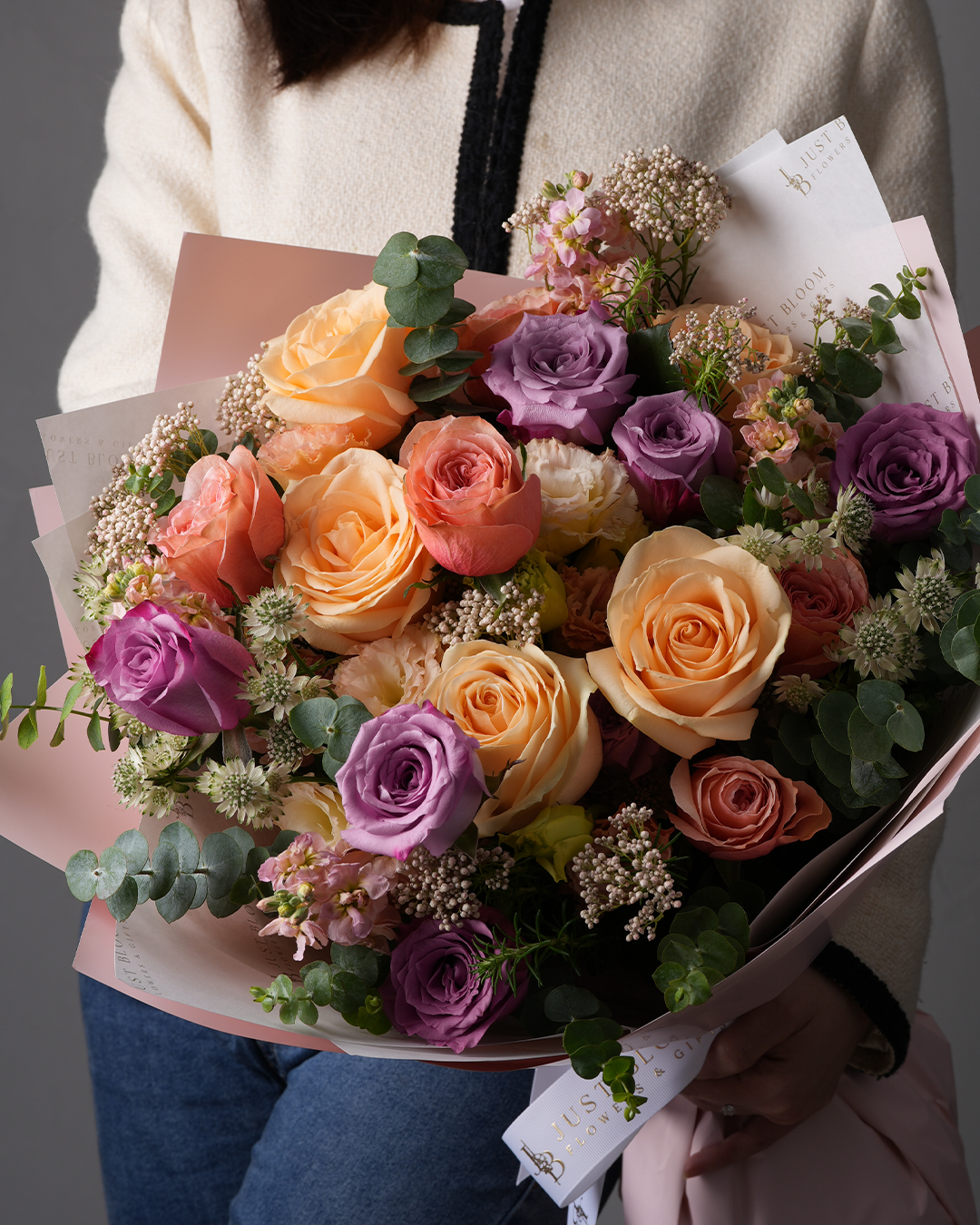 Close-up of Hadley bouquet with peach roses, purple eustomas, and rice flowers – elegant floral gift for birthdays or anniversaries