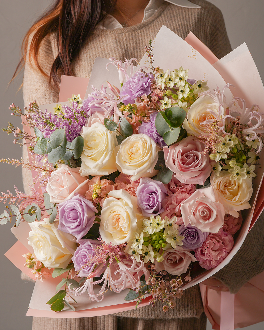 Close-up view of Lauren bouquet showing roses, carnations, and spider lilies in pink wrapping