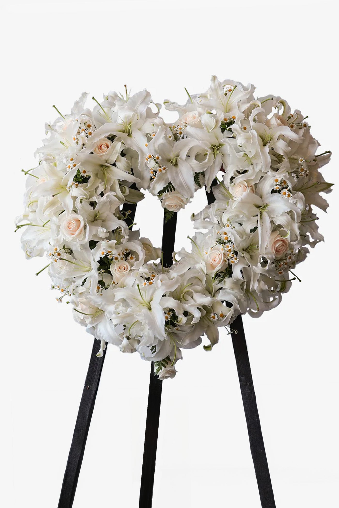  white lily and rose funeral wreath arrangement on black stand with circular design