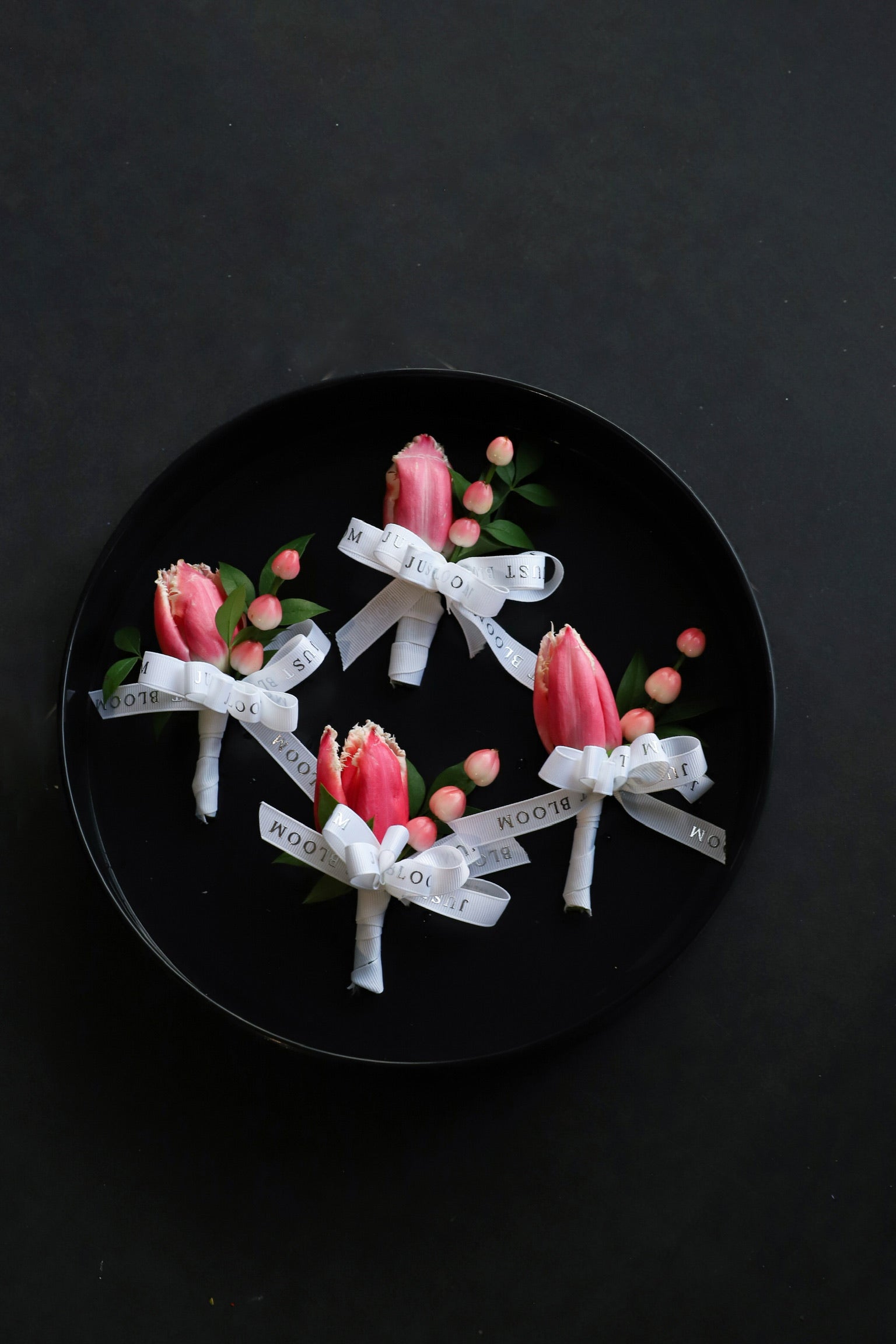 Close-up of four Always & Forever wedding corsages on a black tray by Just Bloom Hong Kong, showcasing pink fringed tulips and hypericum berries with Just Bloom white ribbon