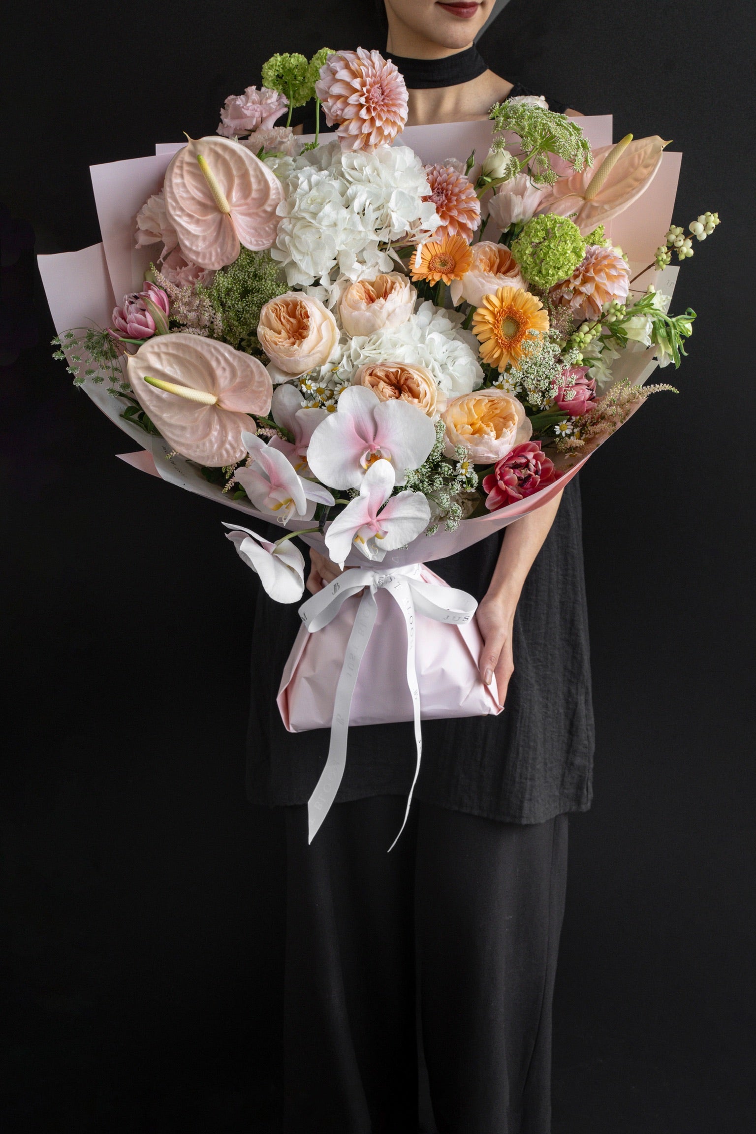 Model holding the Apricot Garden bouquet of peach and white blooms against a black backdrop — Just Bloom Hong Kong