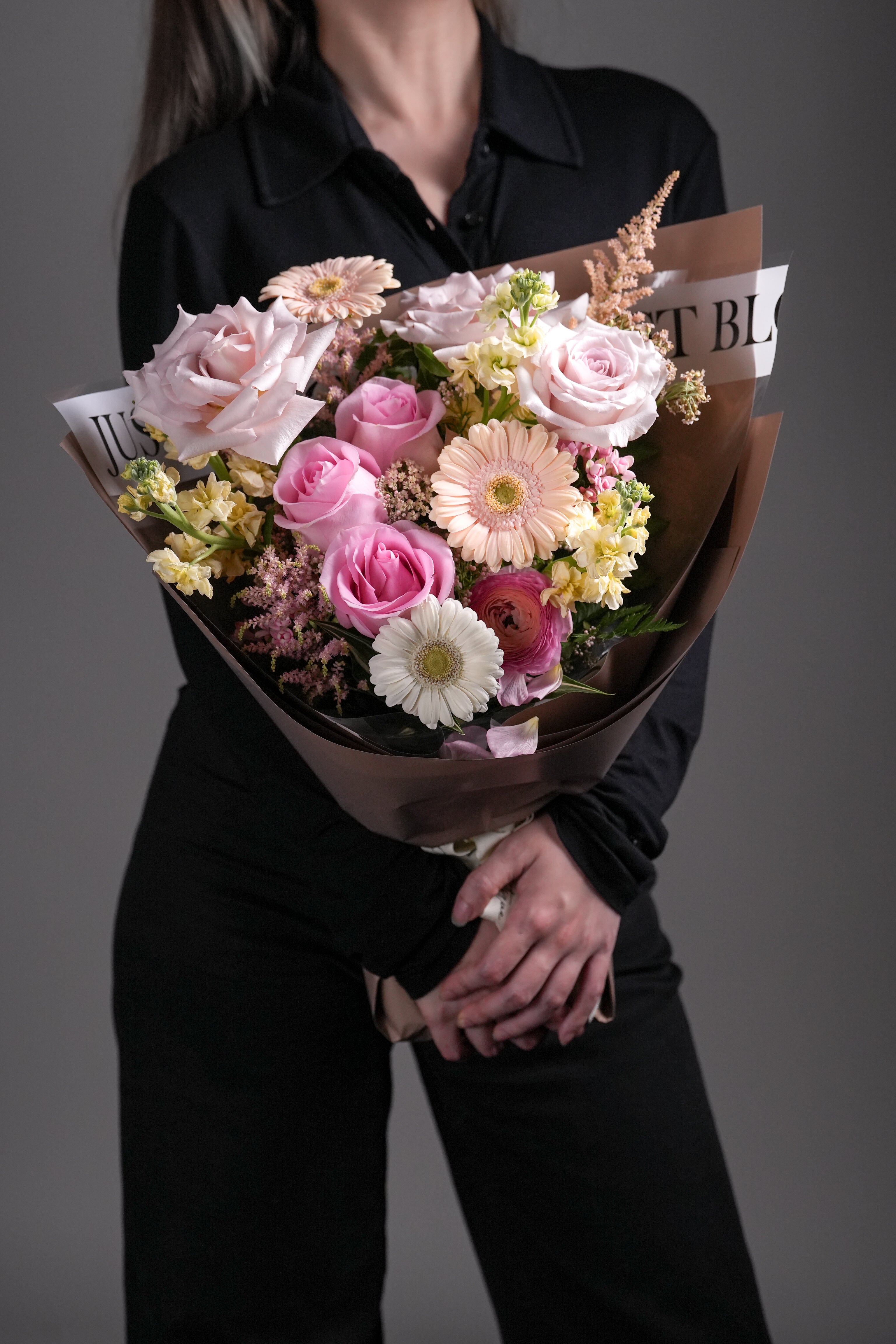 Side view of model holding Asher bouquet in light pink wrapping.