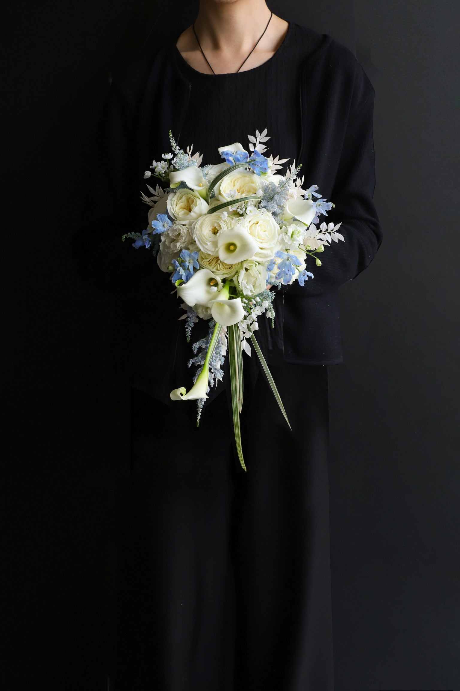 Model in black dress holding a cascading bridal bouquet in soft white and periwinkle blue with a long trailing form — Just Bloom Hong Kong