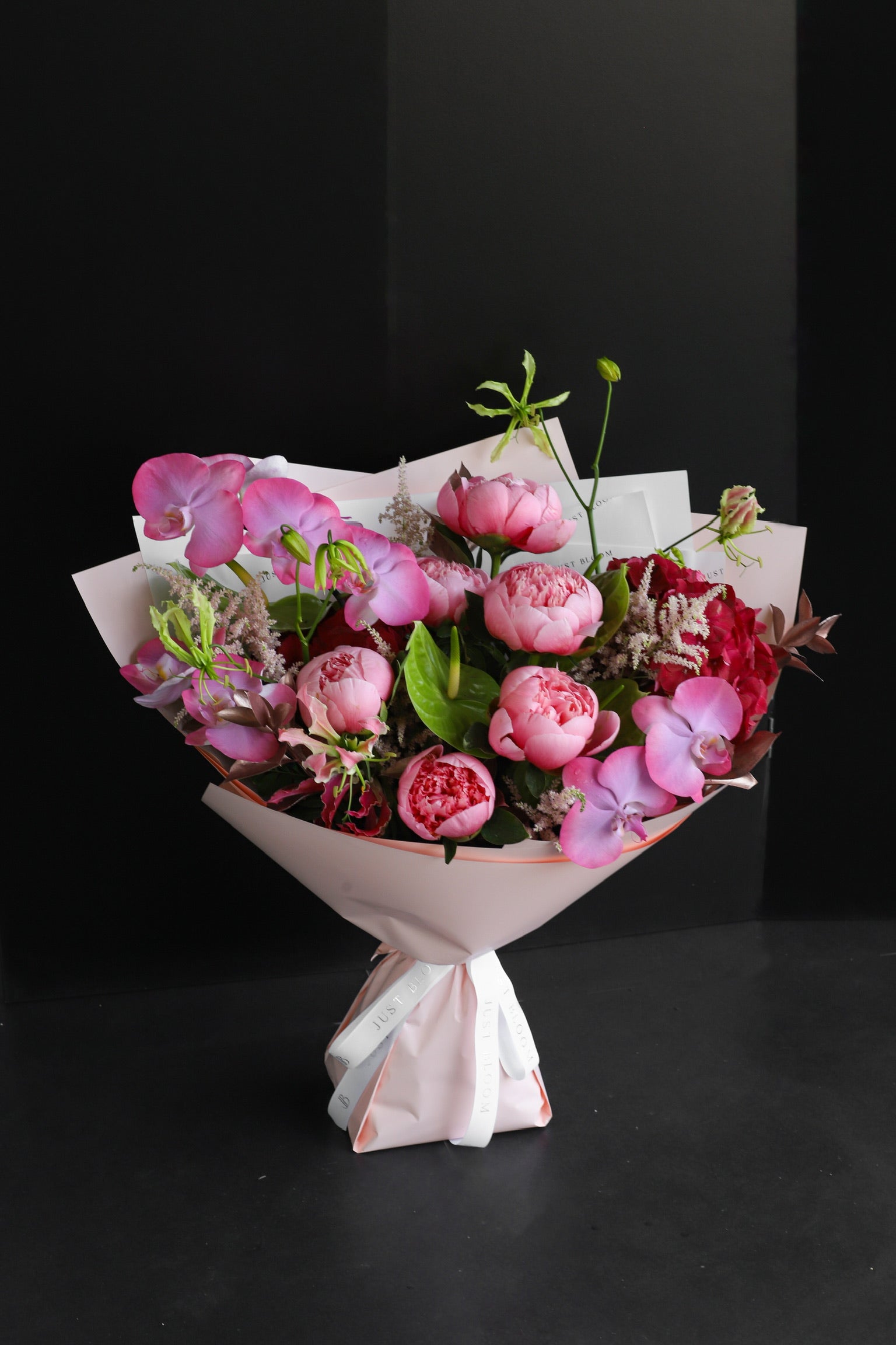 Bloom Theory luxury bouquet by Just Bloom Hong Kong featuring pink peonies, phalaenopsis orchids and astilbes in blush pink wrapping with Just Bloom white ribbon