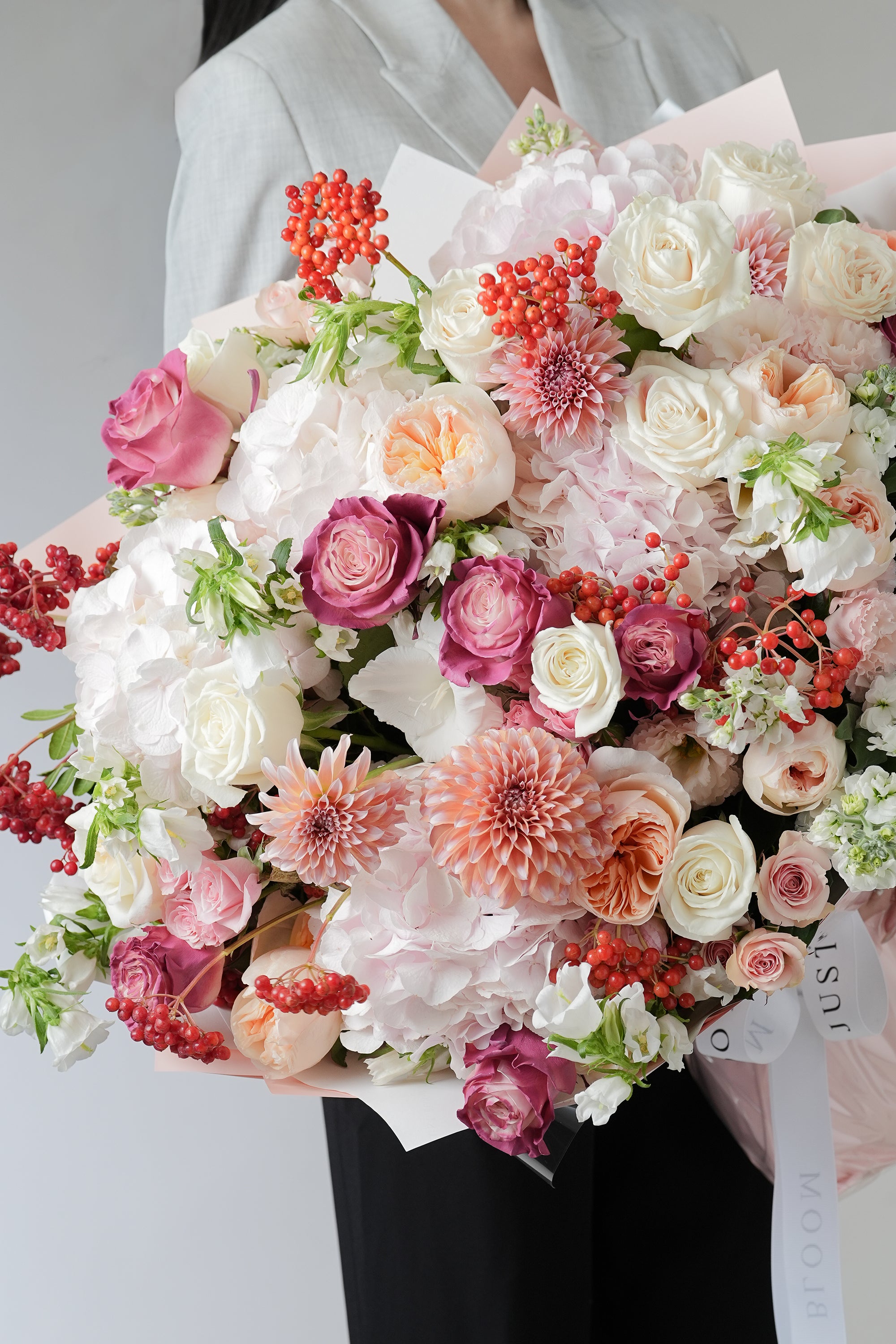 Blush Symphony luxurious bouquet featuring spray roses, bell flowers, hydrangeas, and seasonal fillers in pink and coral